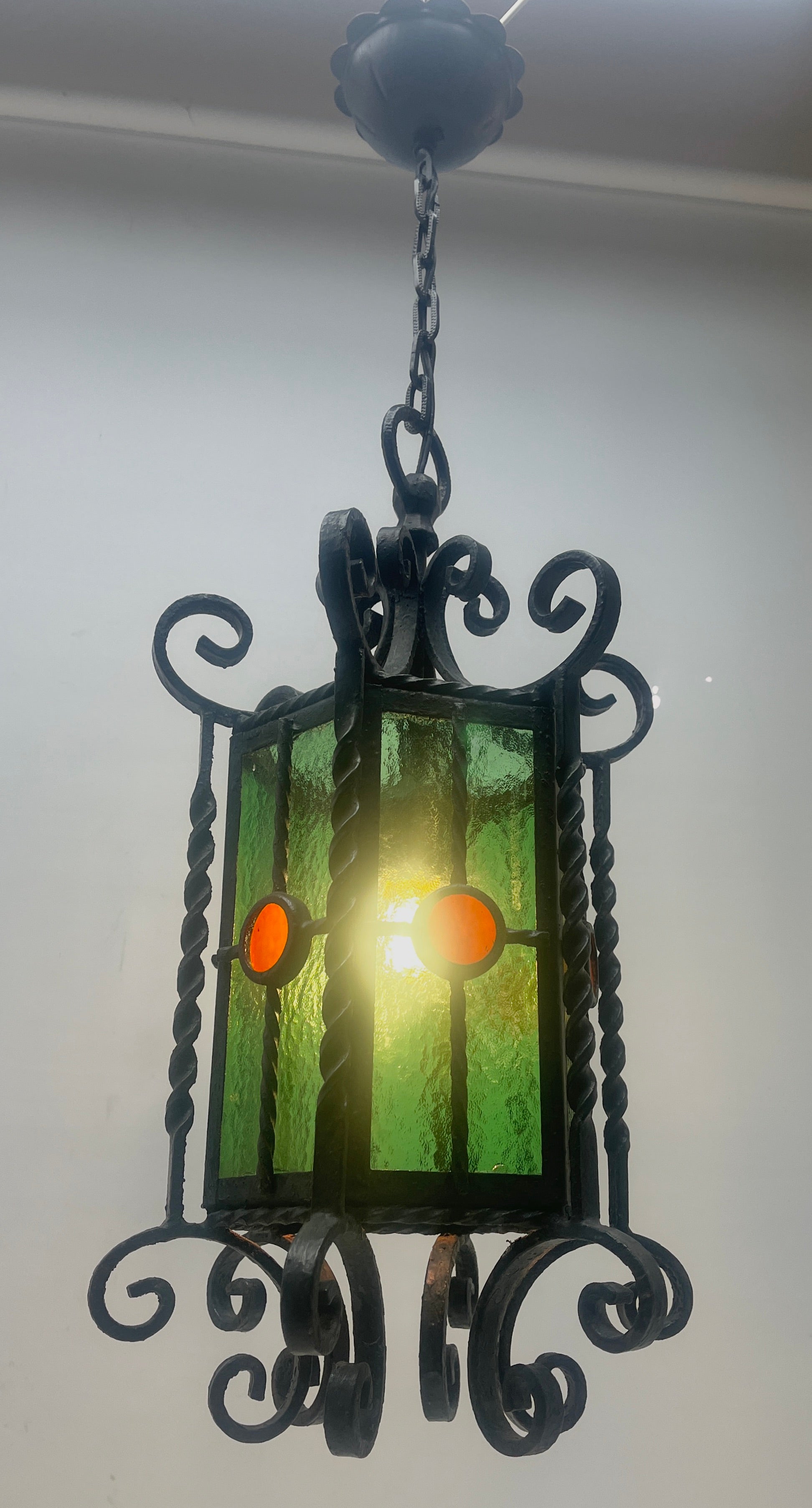 Forget and colored glass pendant lamp.
Materials: Colored glass Black painted curved iron slats pleated as a cage.
Metal chain and canopy. E27 socket.
Original patina on all parts.

In Good condition and in full working order. 
And safe for
