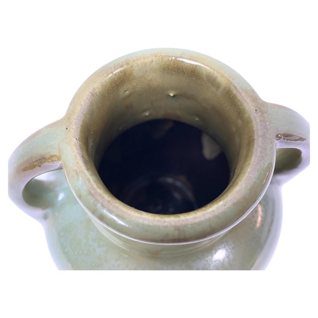 Poterie américaine antique Fulper avec deux poignées et une marque ovale incisée (vers 1917-1927). Le vase est de couleur verte et brune, avec de fines taches sur la surface.

Dimensions : 6