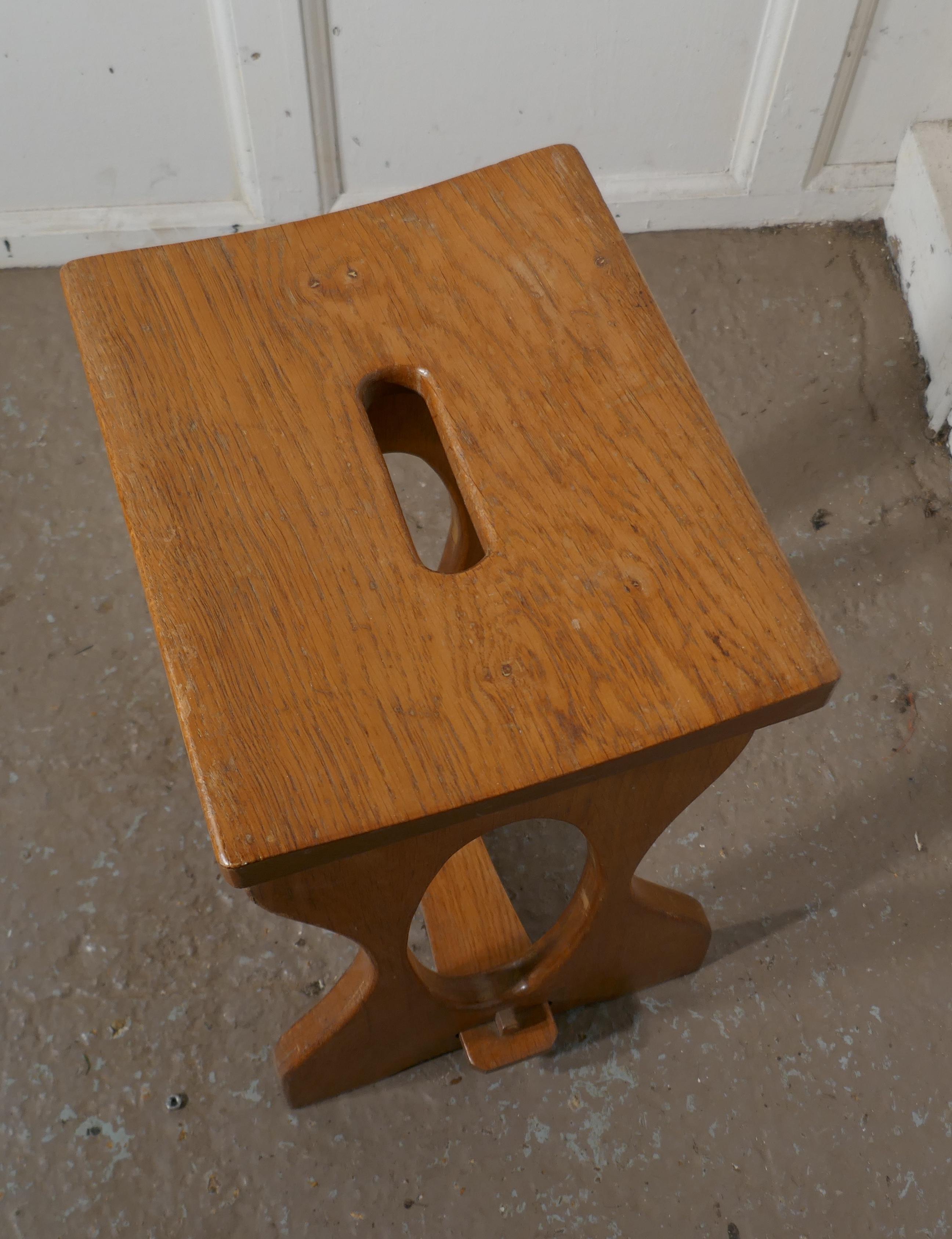 Arts & Crafts golden oak stool

This is a very unusual piece it made in 1” thick oak and has a curved top, it is thicker at each side than it is in the center where it has a hand carrying opening
The stretchered legs have an oval cutout in the