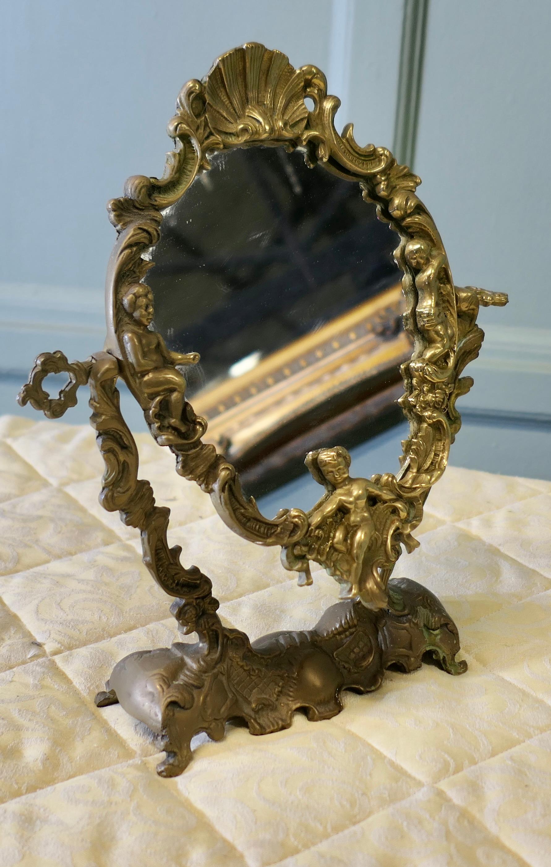 Arts and Crafts Gothic Style Brass Mirror

A classic of its style, this easel mirror has a pretty oval shape, with a very decorative brass frame depicting cherubs and shells
All in good condition for its age, the mirror is 13” tall, and 12” wide
ST37