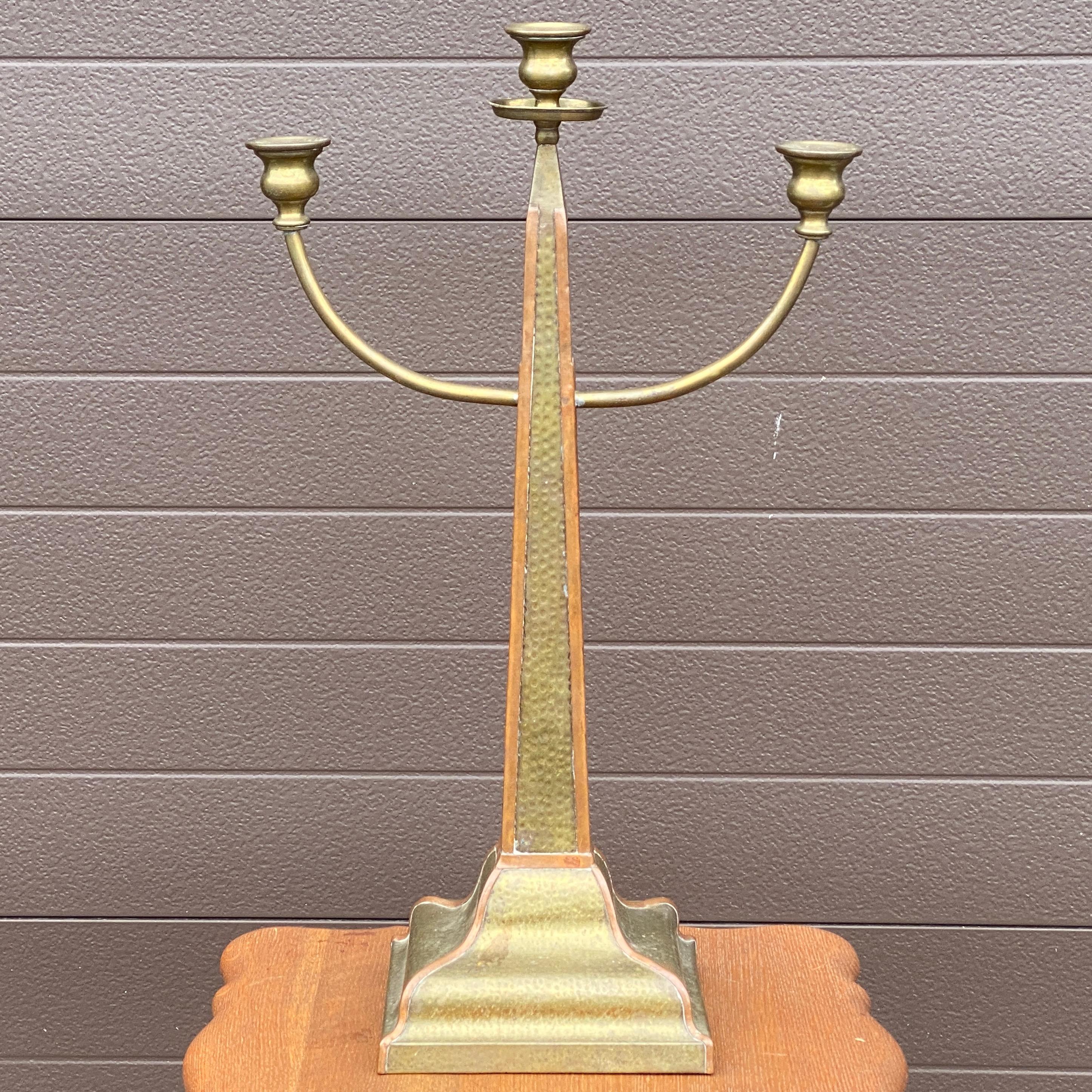 A unique obelisk shaped candelabra in hammered brass and trimmed in copper. Unmarked
Base measures roughly 7.25” x 6.25”