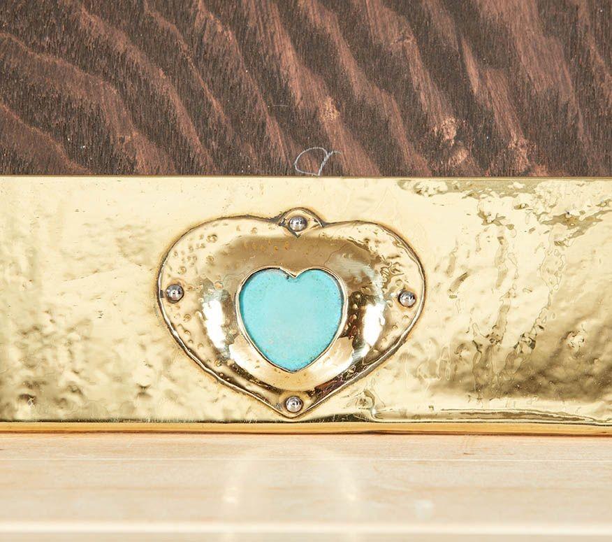 An English Arts & Crafts brass picture frame with a hand-hammered surface featuring overlapping seams pinned with brass studs and raised heart shaped bezel framing a turquoise cabochon. Suitable for picture display on a flat surface or could be set
