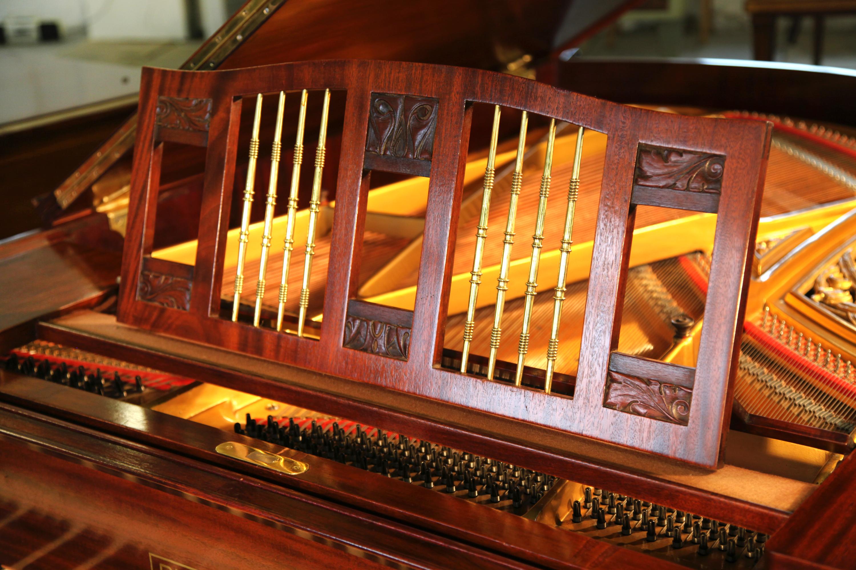 A 1916, German Arts and Crafts, Ibach grand piano with a mahogany case and carved panel detail. The mahogany cabinet is polished so as to emphasize the quality of the wood used. The minimal rectangular lyre has two rectangular uprights separated by