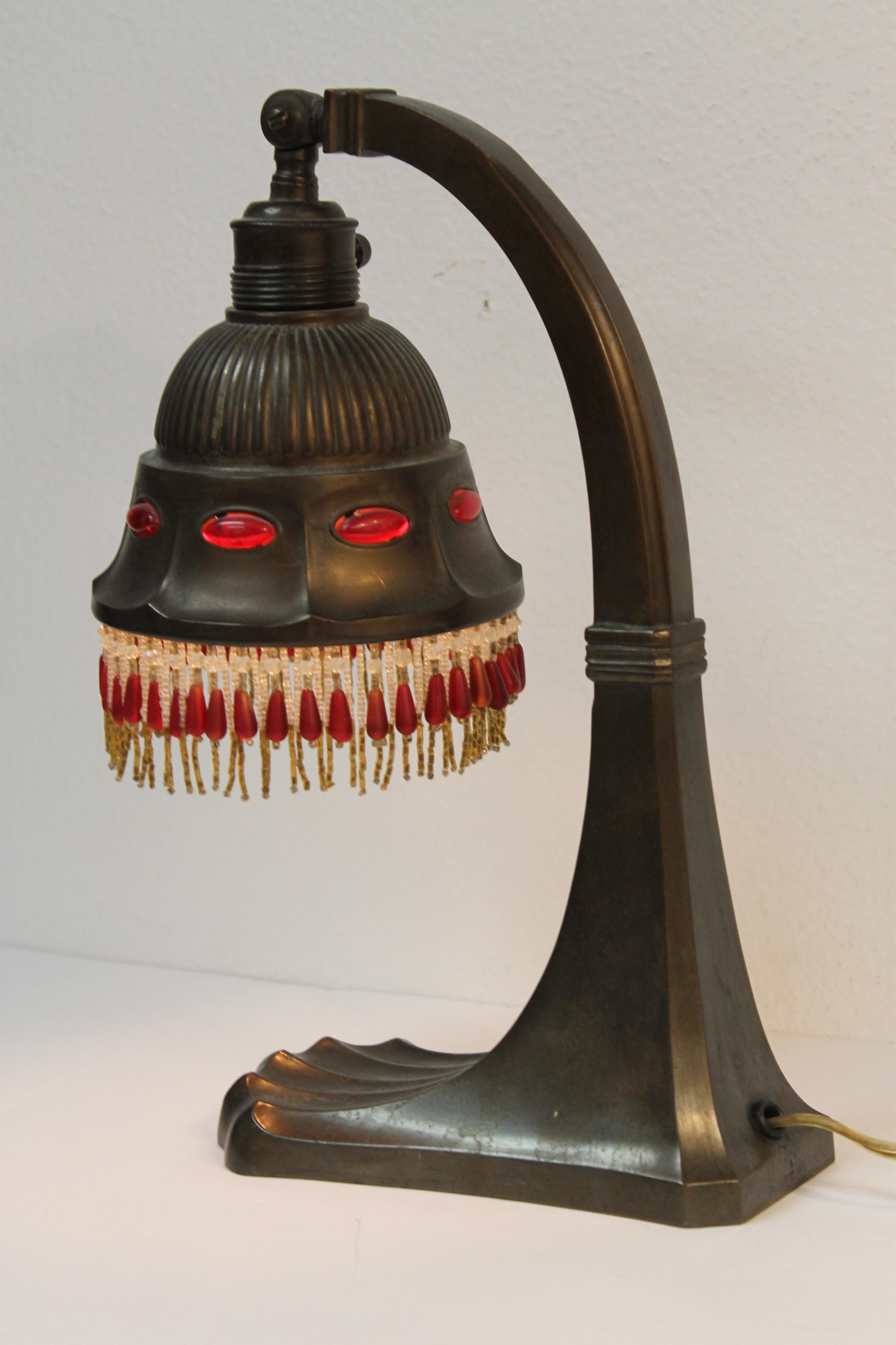 An early 20th century small accent light, brass with red glass lozenge shaped jewels set into the shade. Glass beaded fringe. Lamp measures 12.5