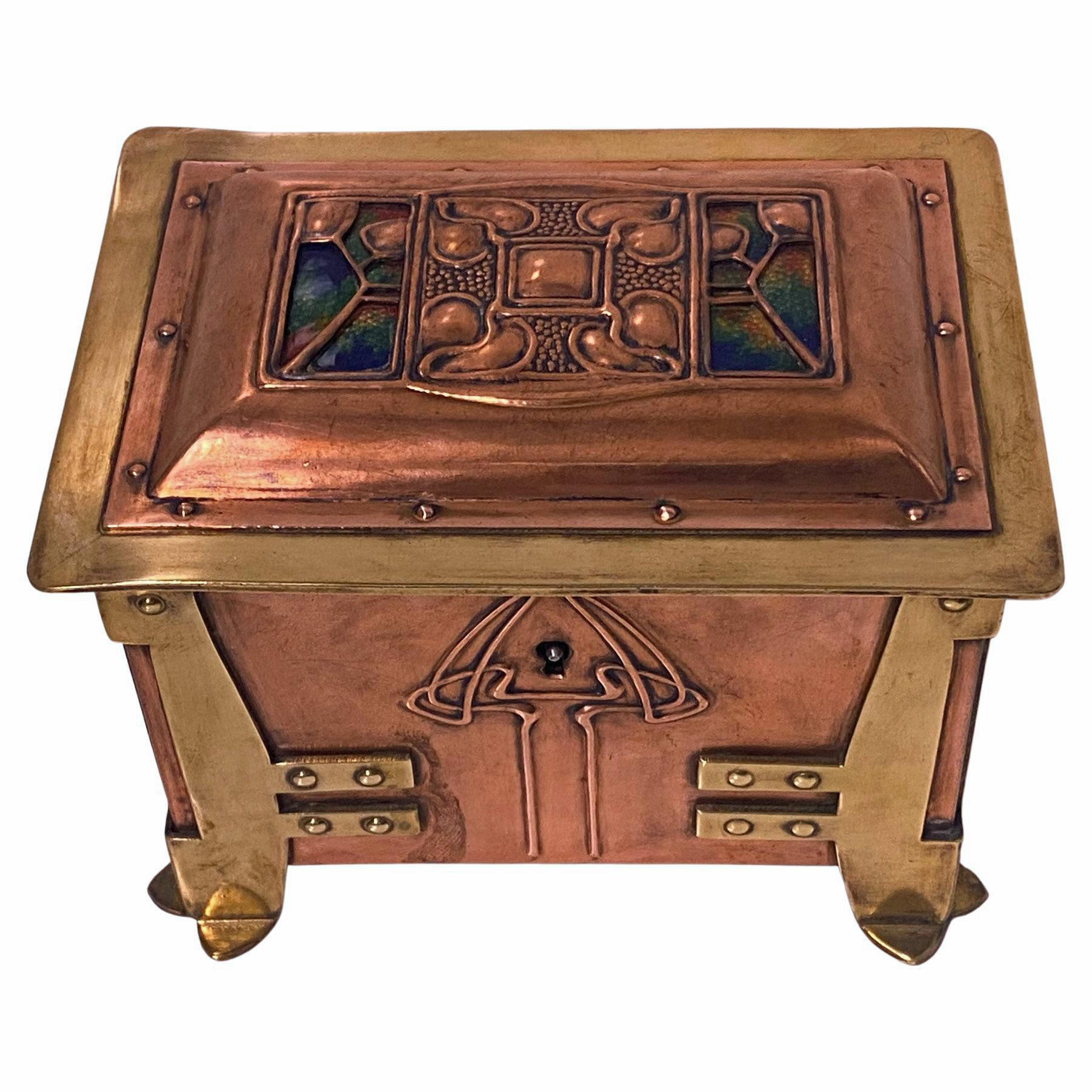 Arts and Crafts Art Nouveau Jugendstil Enamel, Copper and Brass Box, C.1900. The box on four turned bracket brass splay petal supports, the paneled copper and brass rivet body with stylised arts and crafts decoration, the cover and front with enamel