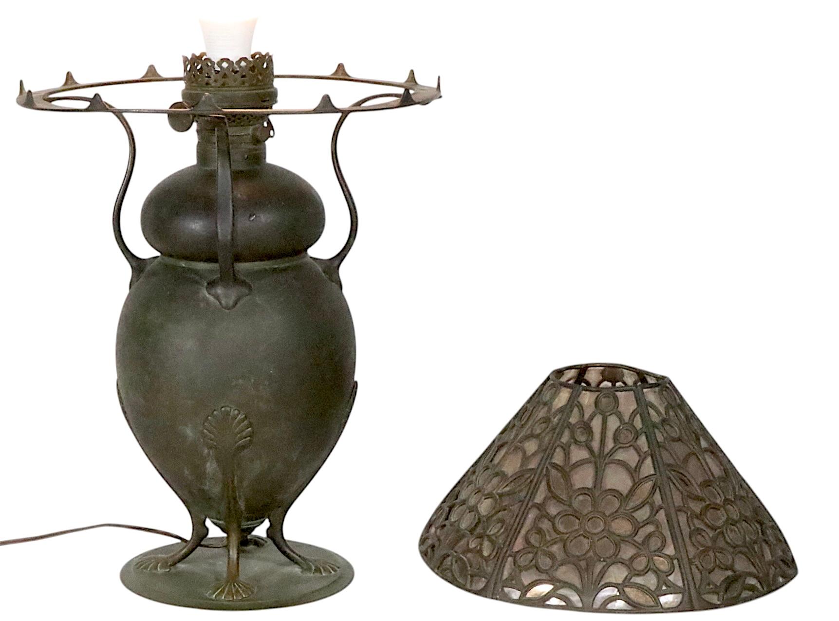 Exceptional Arts and Crafts, Art Nouveau table lamp, with bronze base, bronze and mica shade.  The lamp features an organic vase form base, with stylized legs, and arms, which support the cone form filigree bronze and mica shade. This example is in