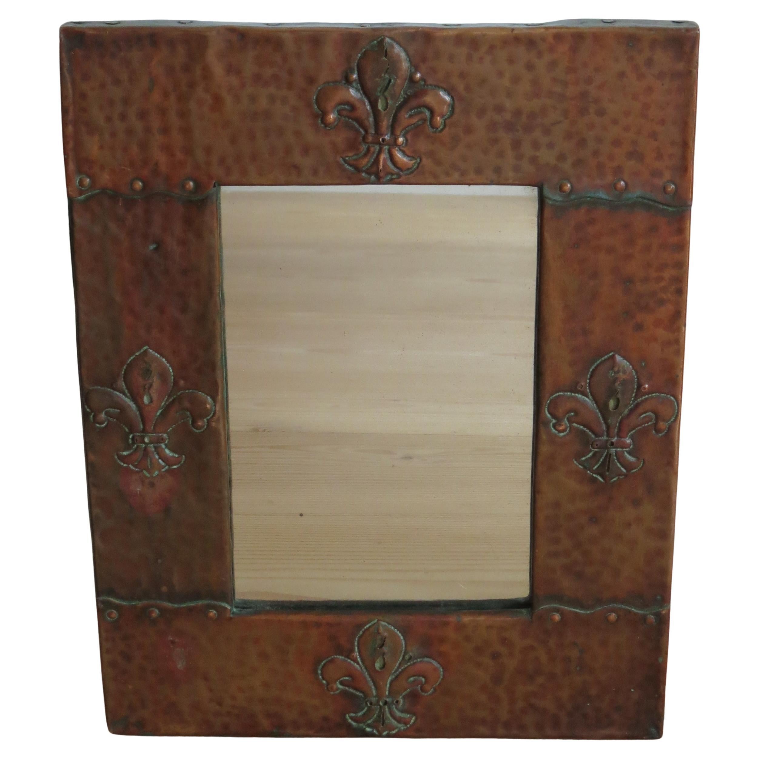 Magnifique miroir mural Arts and Crafts. Dates des années 1900
Cadre en pin avec revêtement en cuivre, détails rivetés sur le cadre et merveilleuse décoration Fleur de Lys. 
Le miroir d'origine a été conservé et ne présente que des taches minimes. 