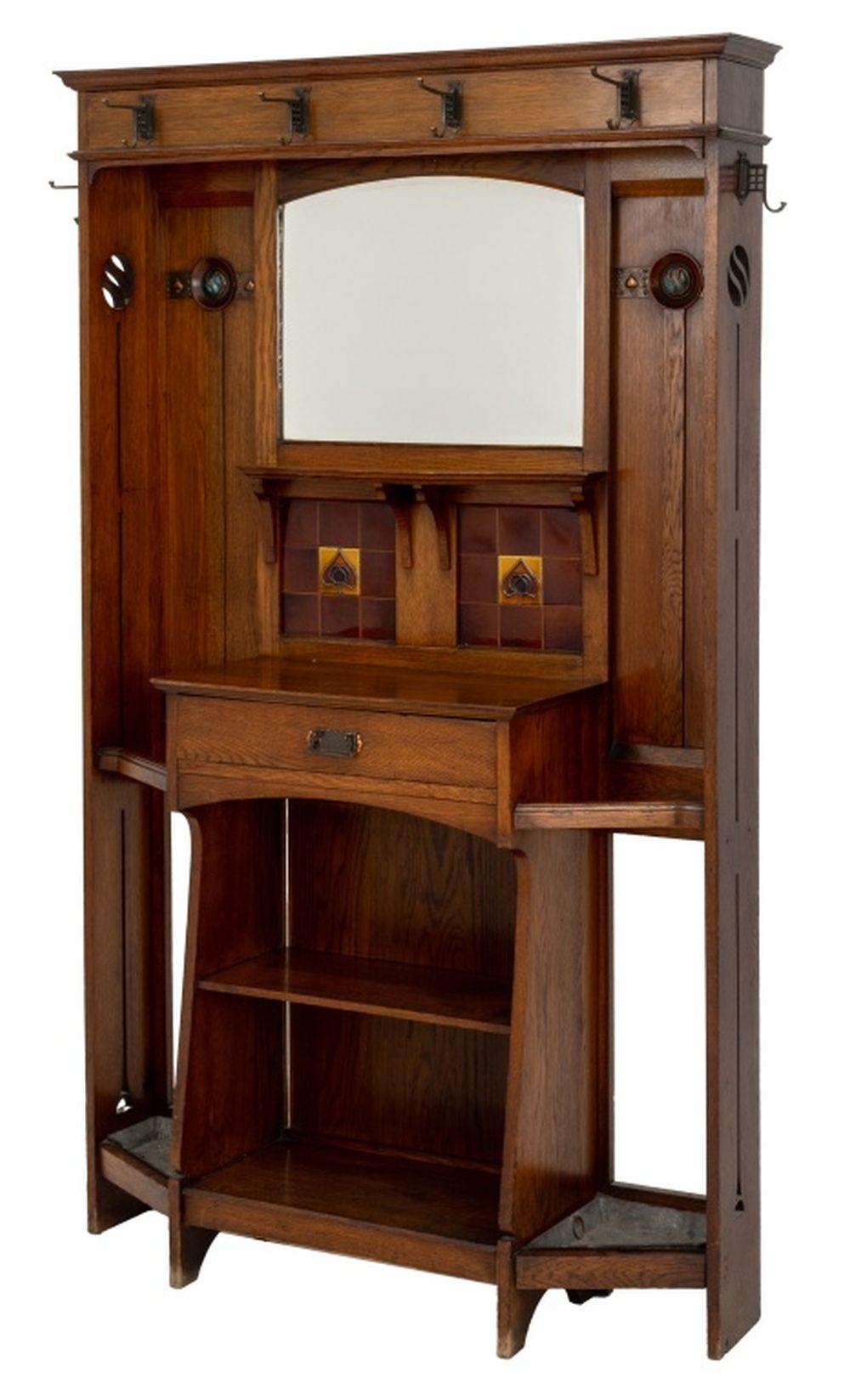 Arts and Crafts Mirrored Oak Hall Stand, early 20th century, with four wrought iron hooks, rectangular beveled mirror above red glazed floral motif tile, probably Liberty & Co., with a single frieze drawer, two open shelves, floral hammered copper