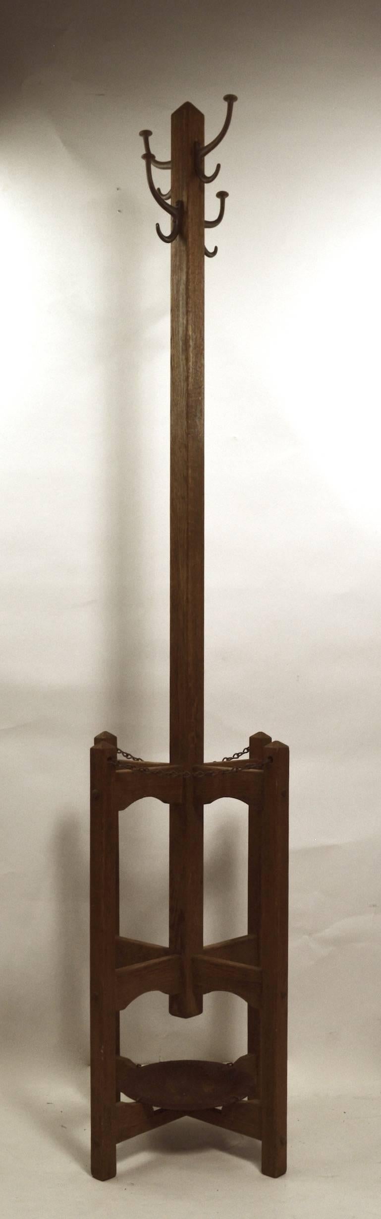 Mission Arts & Crafts coat rack with umbrella holder base. This example is in original condition, showing some light cosmetic wear to finish, and rust on metal tray, normal and consistent with age. Four metal hooks at top (9 inch width at top) each