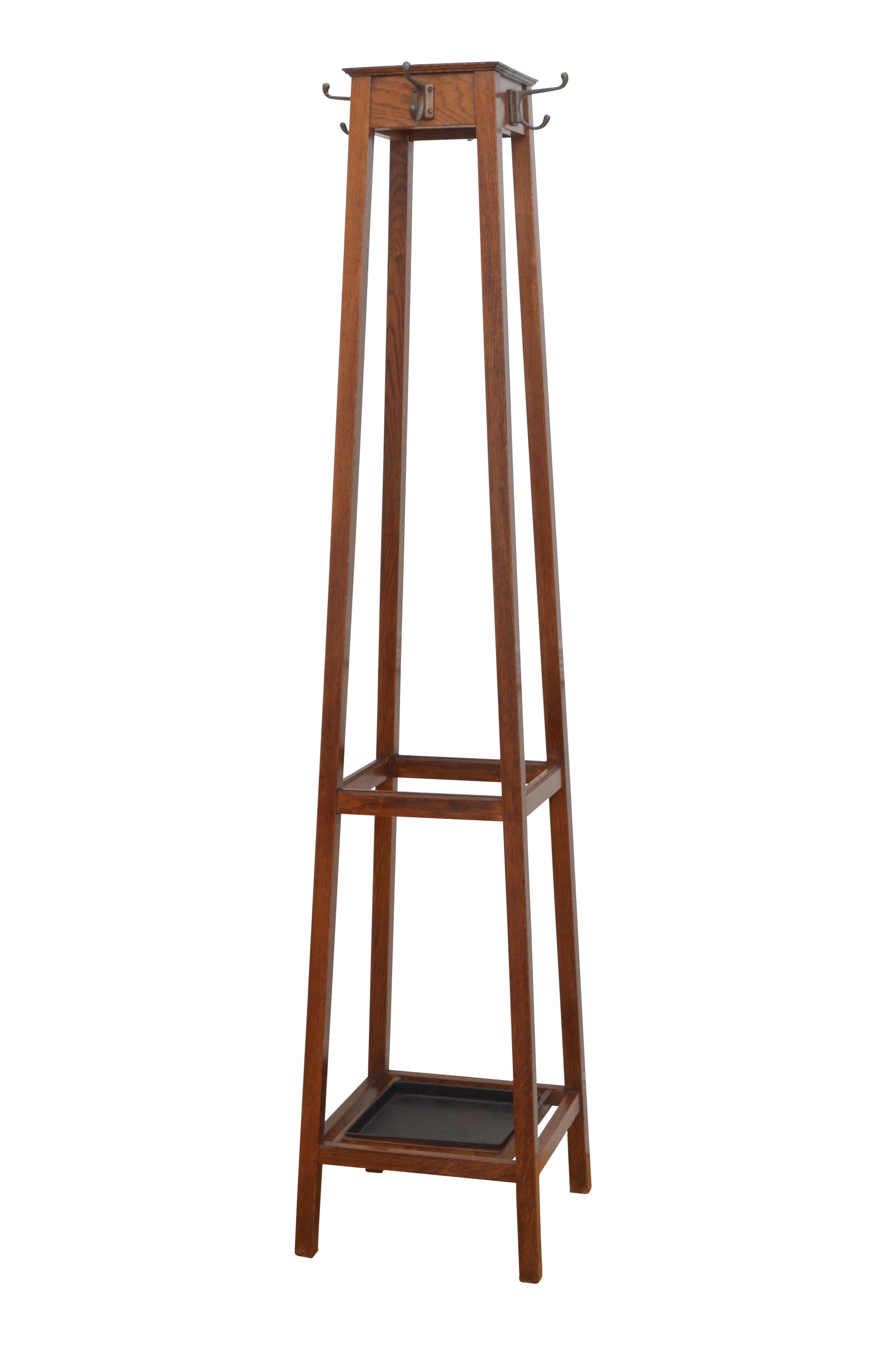 0592 A quality early 20th century solid oak hall stand with original copper plated hooks on four supports united by umbrella and walking sticks holder, with removable drip tray between. This antique coat stand retains its original finish which has