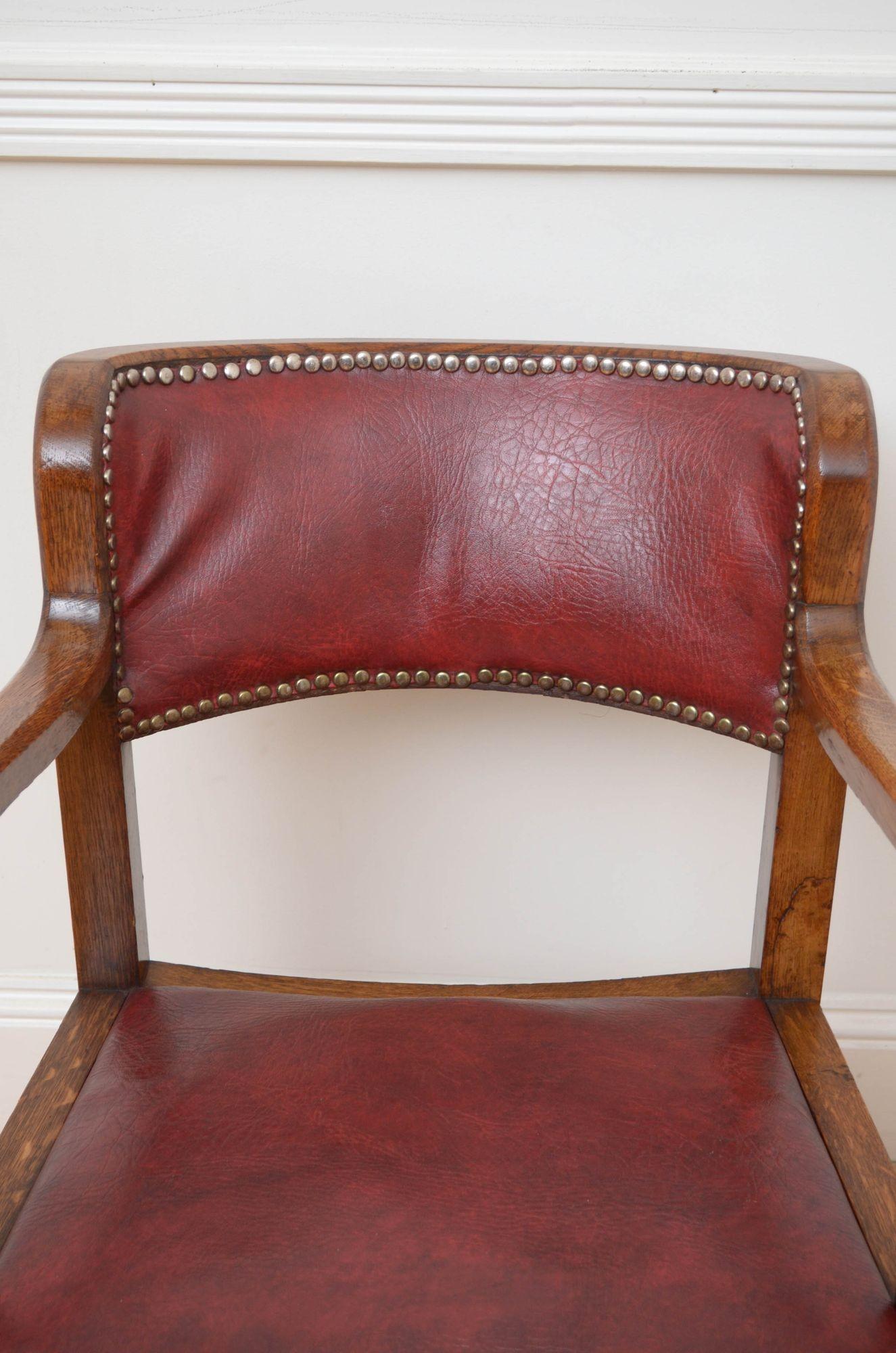 Sn5364 Stylish Arts and Crafts office chair / desk chair in oak, having shaped top rail with closely studded leather and drop in leather seat, both showing minor signs of usage, open, scroll arms and shaped legs united by a stretcher. This antique