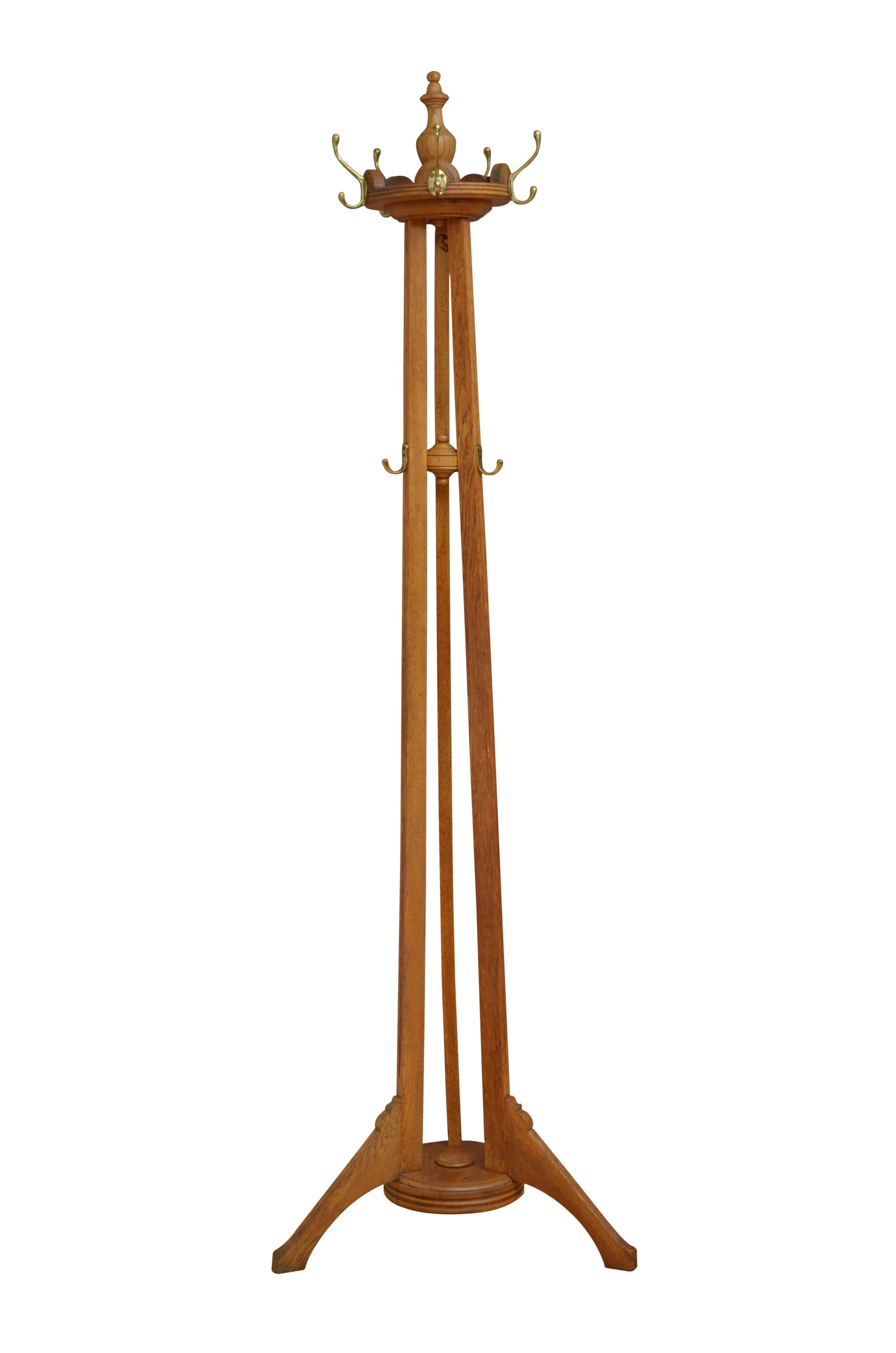 K0590 Arts and Crafts oak hat stand, having six brass hooks on revolving platform with finial to the top on 3 solid oak supports with further 3 brass hooks terminating in shaped legs and united by circular base with reeded edge. This antique coat