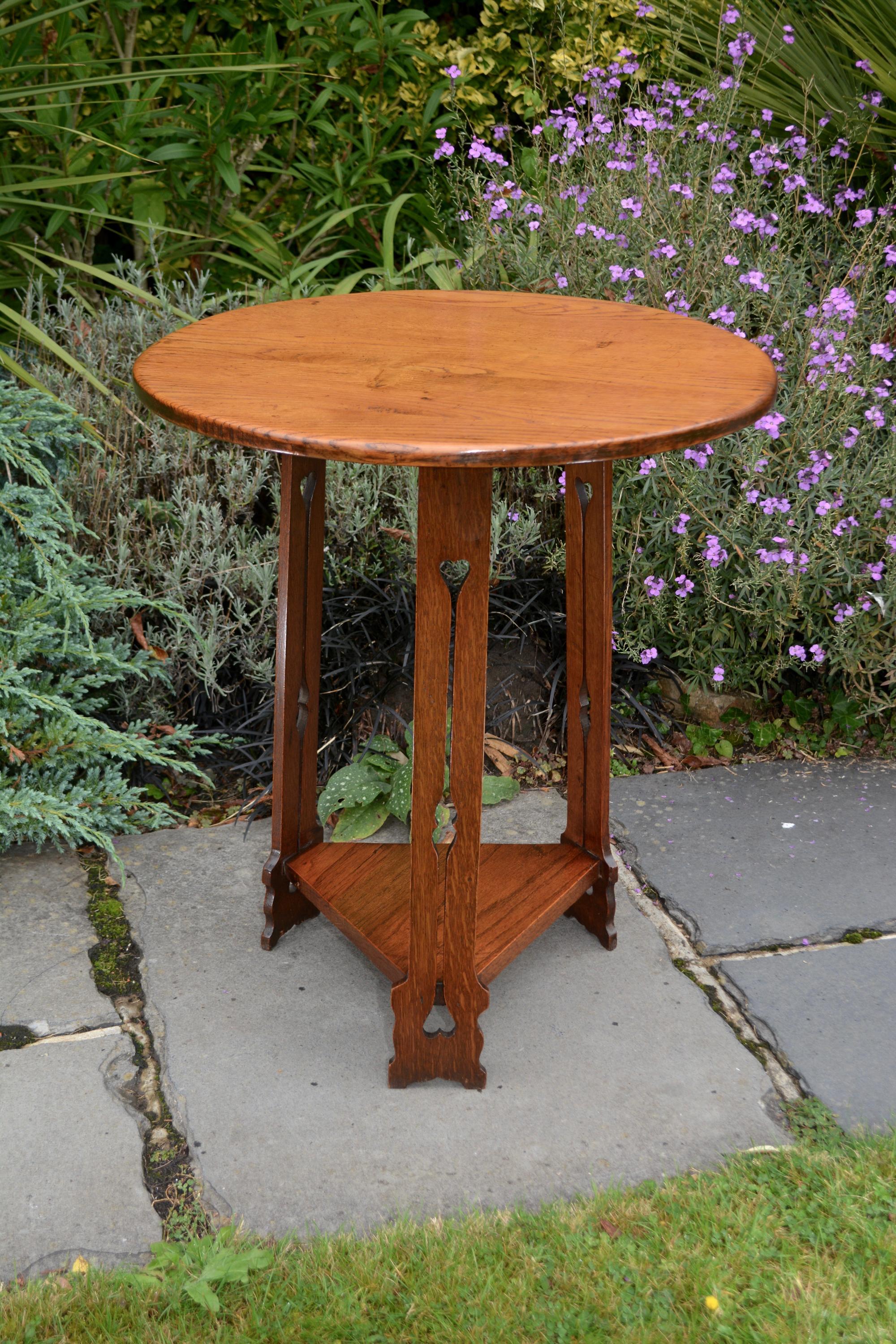 An Arts & Crafts occasional lamp table. Hand made from solid oak and dating from circa.1910. 61cms diameter and 68.5cms tall.