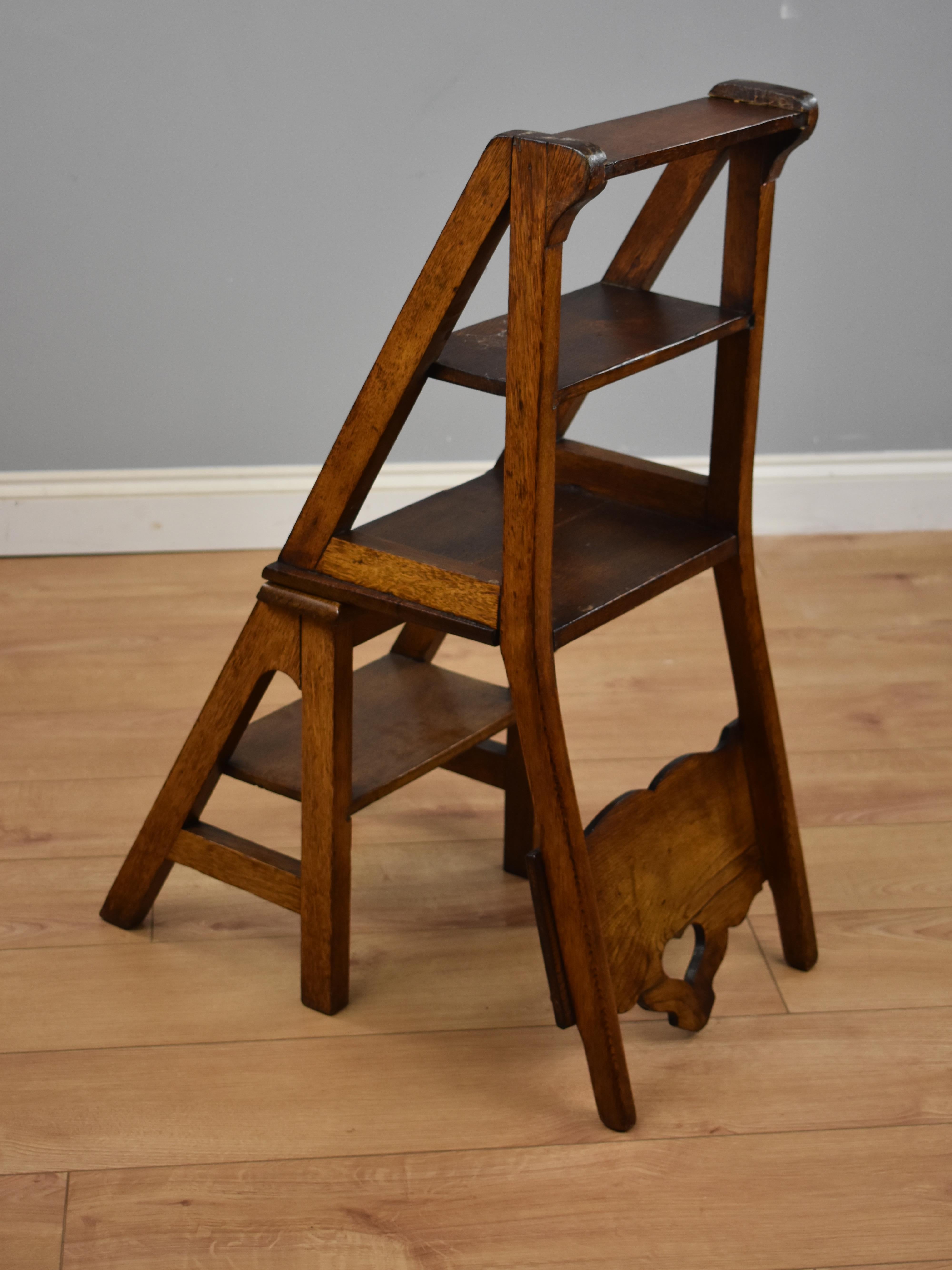 Arts & Crafts Metamorphic chair / library steps with a pierced motif to the back, opens when the locking rod to the side is lifted into a sturdy well constructed set steps. Decorative and functional item.