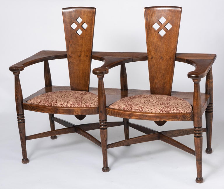 An Arts & Crafts settle designed by George Henry Walton (1867-1933), made by William Birch, high Wycombe.
With Double tapering wedge splats of paddle shape with pierced diamond shapes.
Shaped arms above shaped legs with turning decoration with