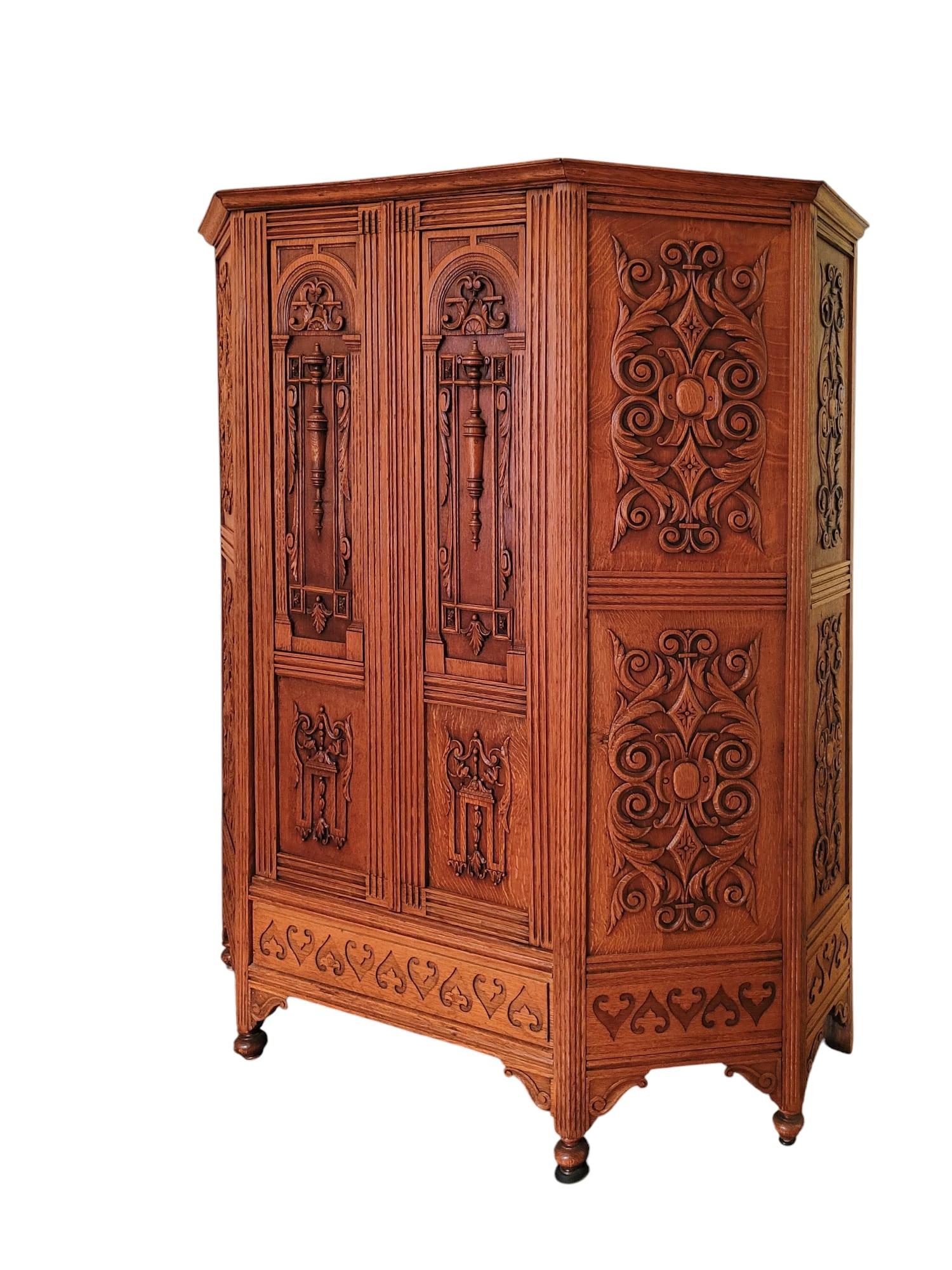 Eine Garderobe/Wäschepresse aus massivem Eichenholz mit einer starken architektonischen Präsenz und detailreichen Schnitzereien. Die Tür weist stilisierte Reliefpaneele auf - bogenförmige Motive oben und strukturierte Schnitzereien unten -, die den