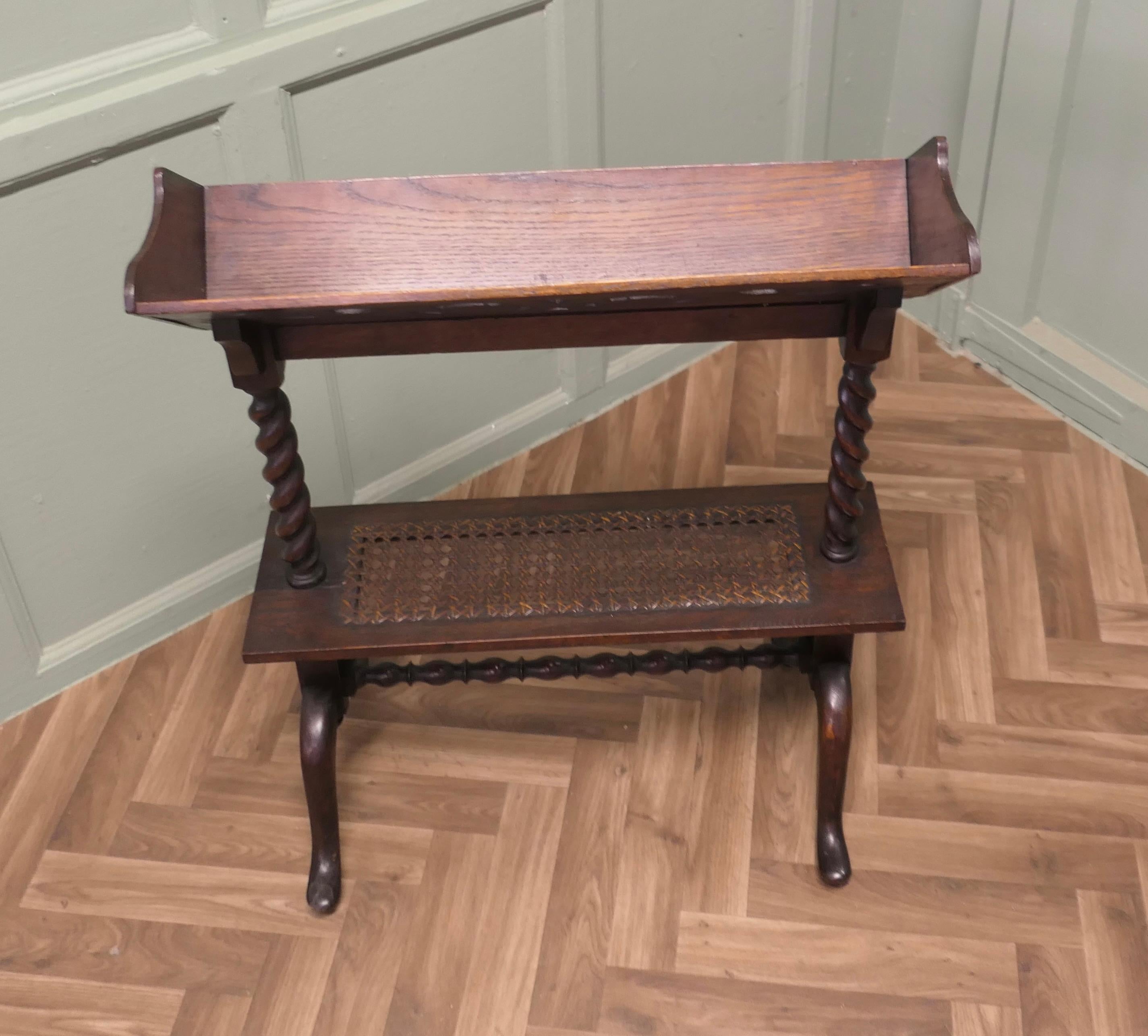 Arts and Crafts Open Front Oak Slope-Shelf Bookcase 

This Oak bookcase has a carved sloped book trough at the top with an under tier made in woven flat cane. 
The bookcase is in good attractive sturdy condition and would work very well in your