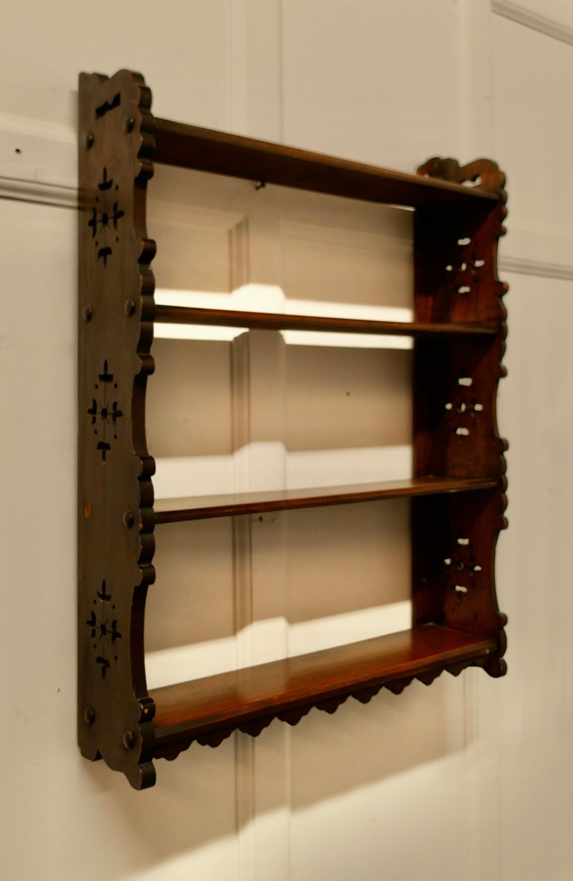 Arts and Crafts open front wallhanging walnut bookshelf.

This oak bookcase has 4 open shelves the bookcase has a carved decoration at each side 
The bookcase is in good attractive and sturdy condition and would work very well in your Living