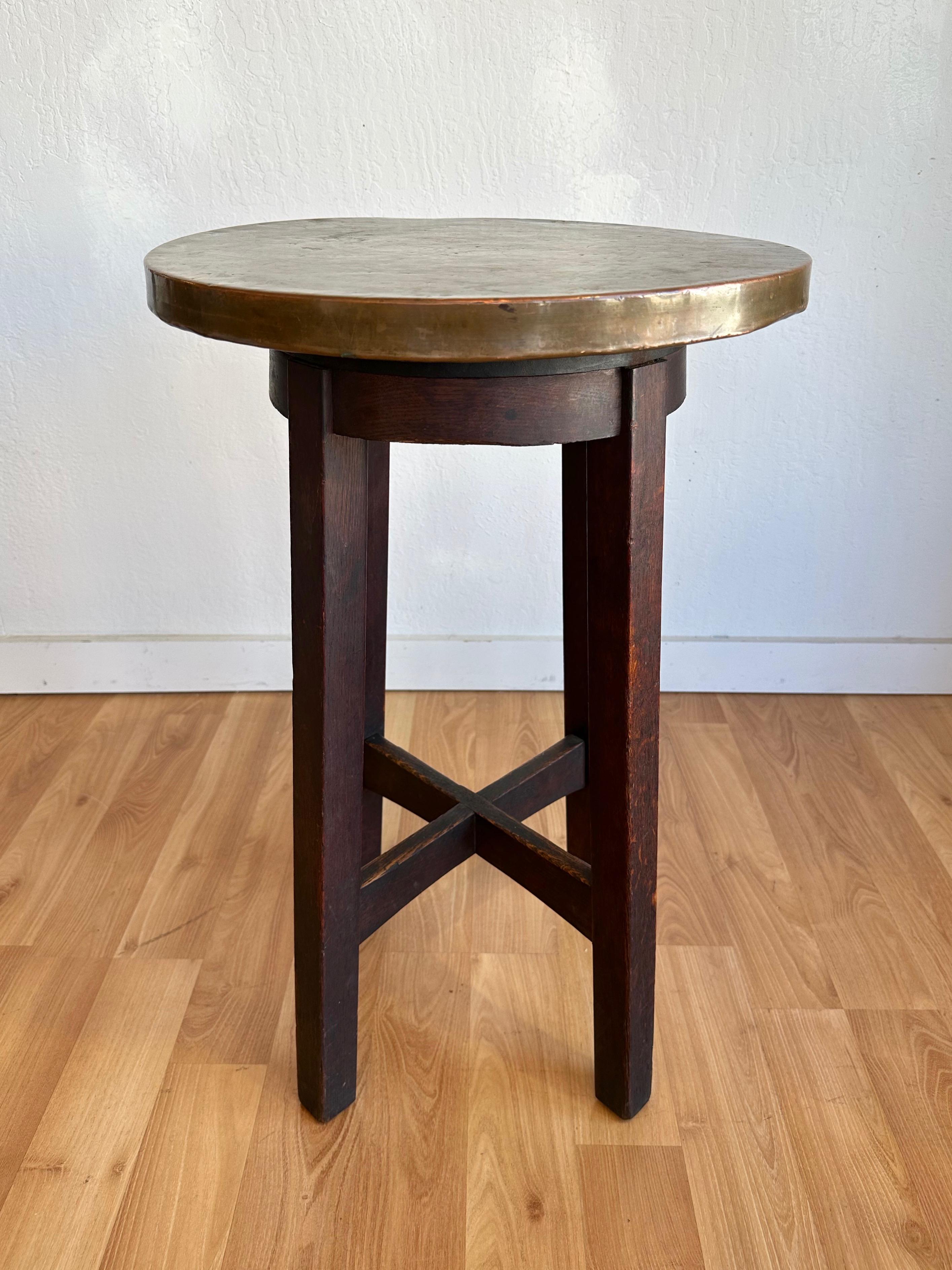 A circa 1920s Arts and Crafts movement or Mission style oak side table or plant stand with copper top.

Round 1.25-inch-thick wood top completely clad in a single sheet of hand-shaped copper. A 1-inch-thick seamless wrought iron band sits inset just