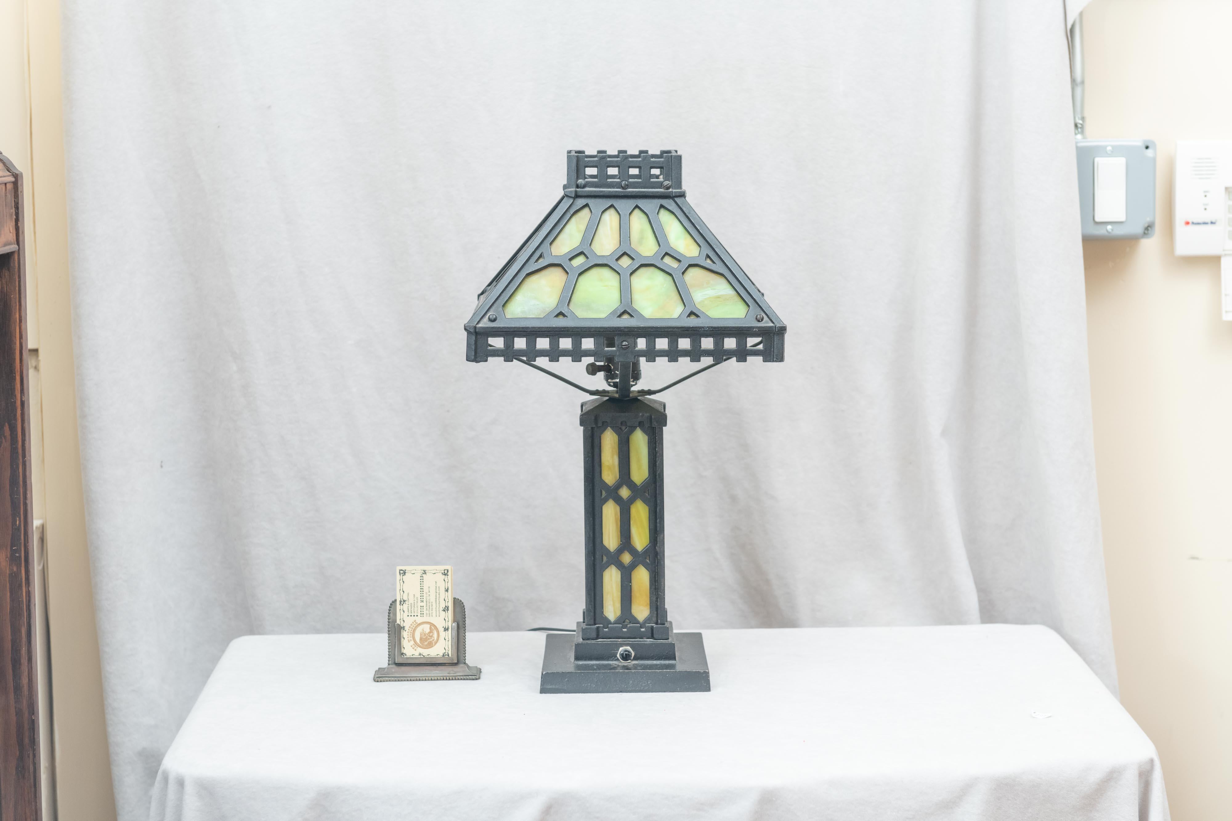 This is a nice example of the Arts & Crafts movement in table lamps. The base is richly patinated cast iron and the glass is original period 