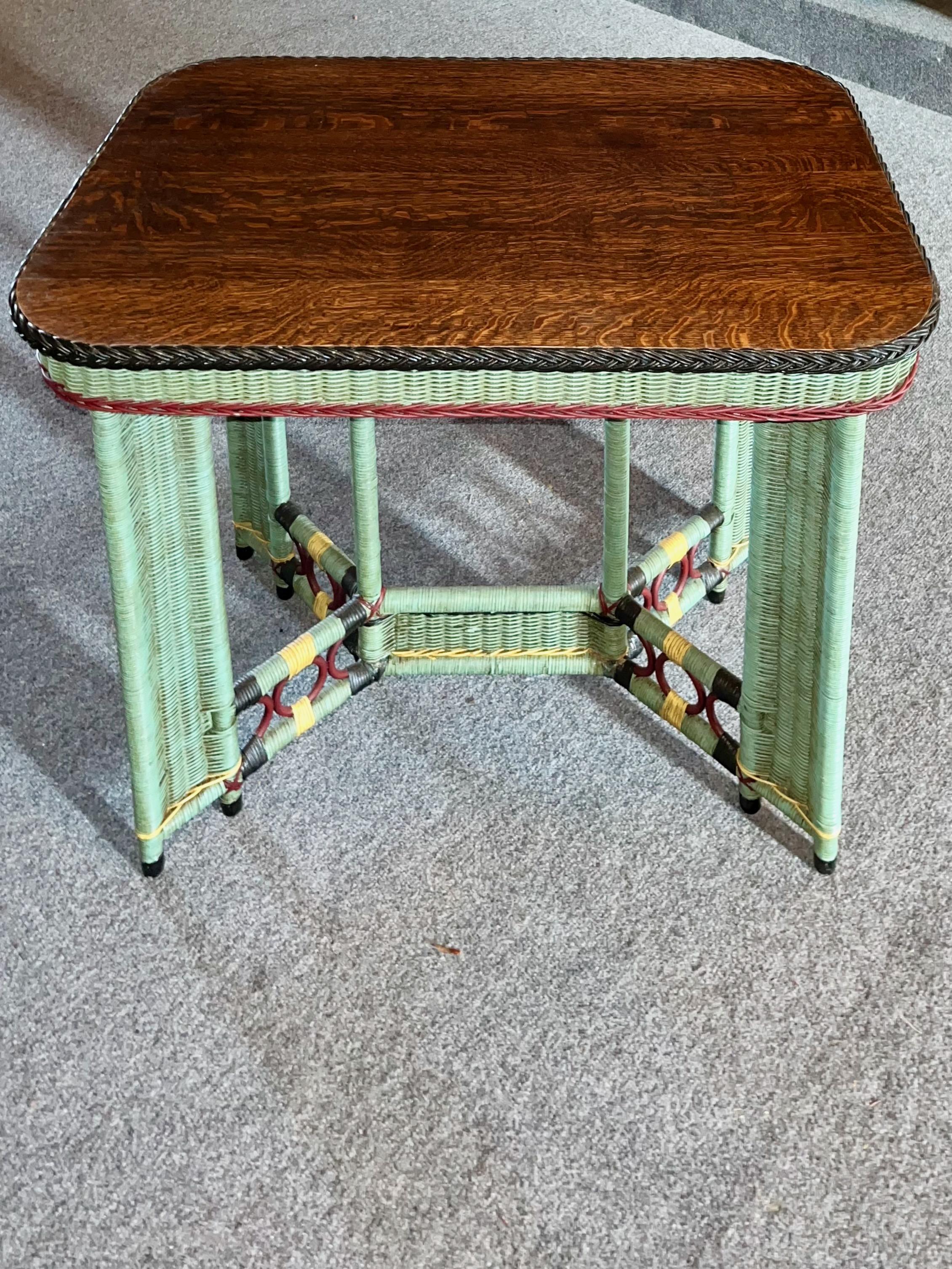 An Arts and Crafts period wicker library / Lamp table C. 1910 from a Rhode Island estate, These tables are a close woven reed done in a turquoise finish with black, yellow and reddish trim colors with the table top done in a very handsome quarter