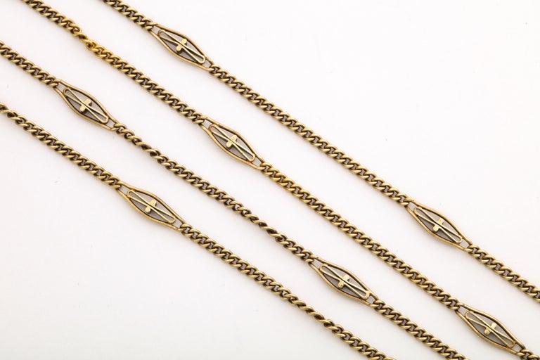 An American made long gold chain that goes on forever or can be divided in two parts. Forever is 65 inches long. intertwined round links are interrupted periodically by oblong links that have a elongated bow shape in their center.. The chain is