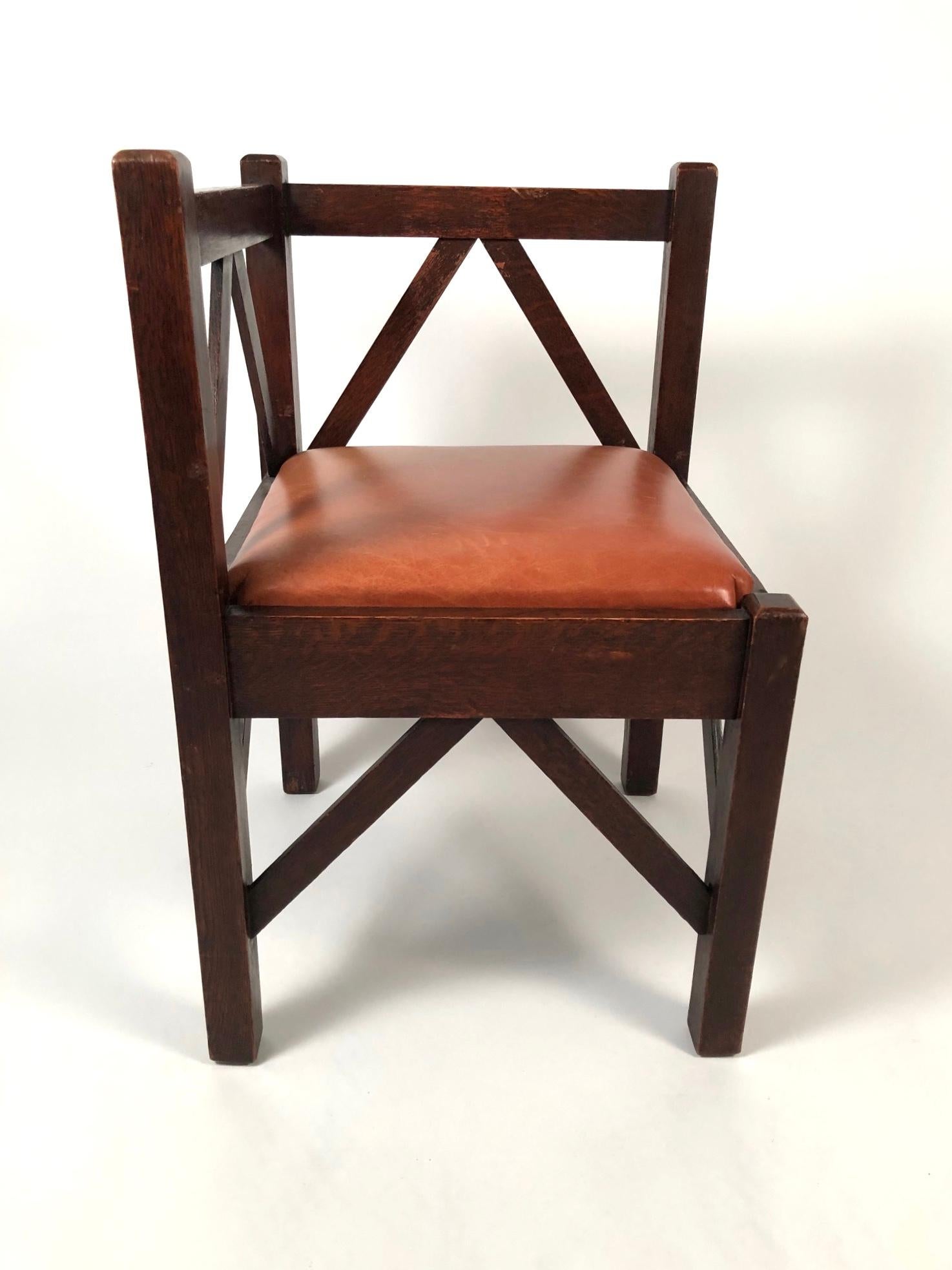 An American Arts & Crafts period corner chair in oak, of wonderfully graphic form and design, in oak, the square section elements-- legs and back rails-- joined by diagonal stretchers which provide strength and give the chair a strikingly modern