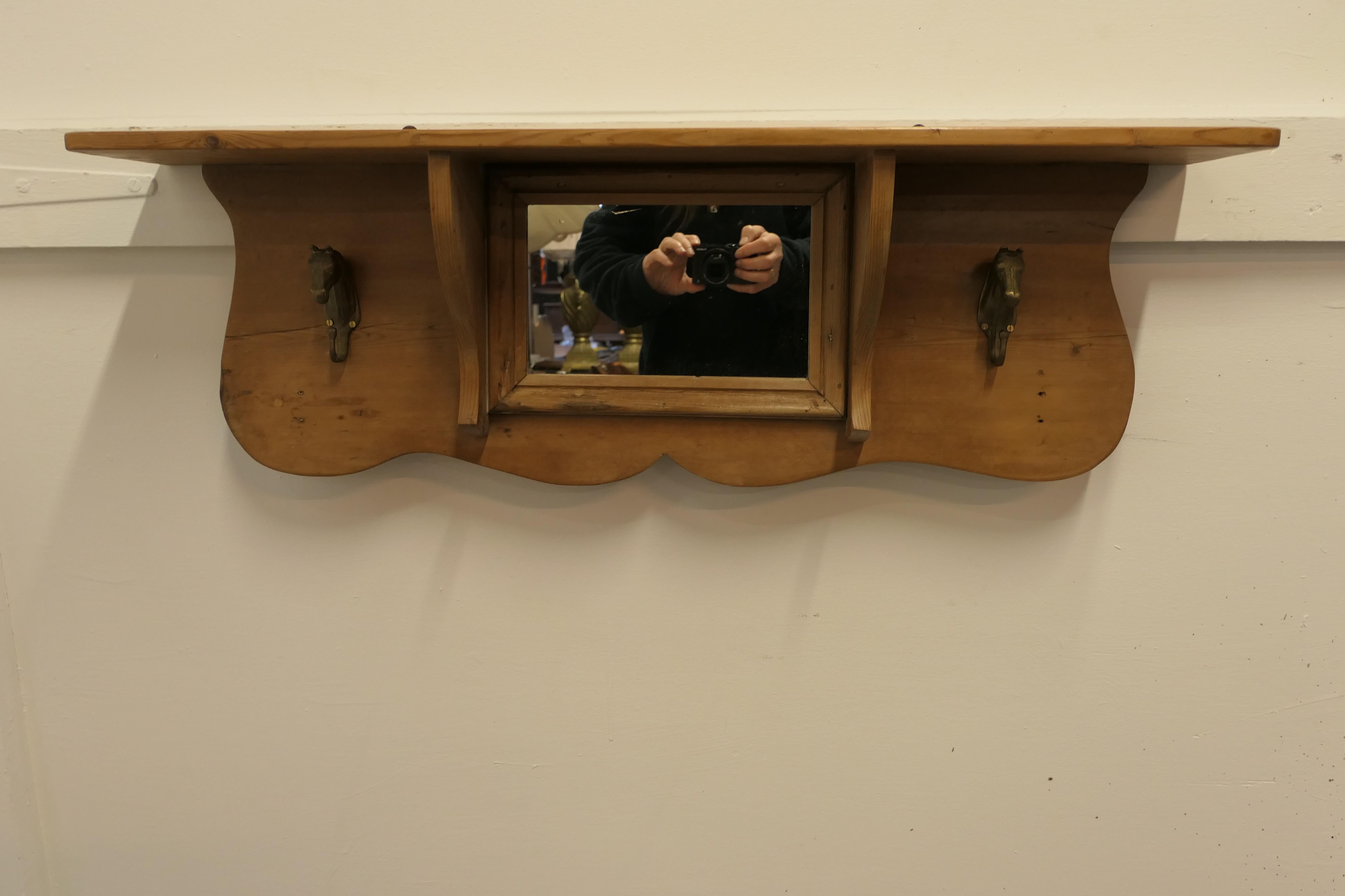 Arts and Crafts pine wall mirror with shelf and horse coat hooks.

This is a very attractive piece, which would work very well in a boot room or cloak room.
The mirror has a small shelf along the top, below this there is the mirror and a Horse