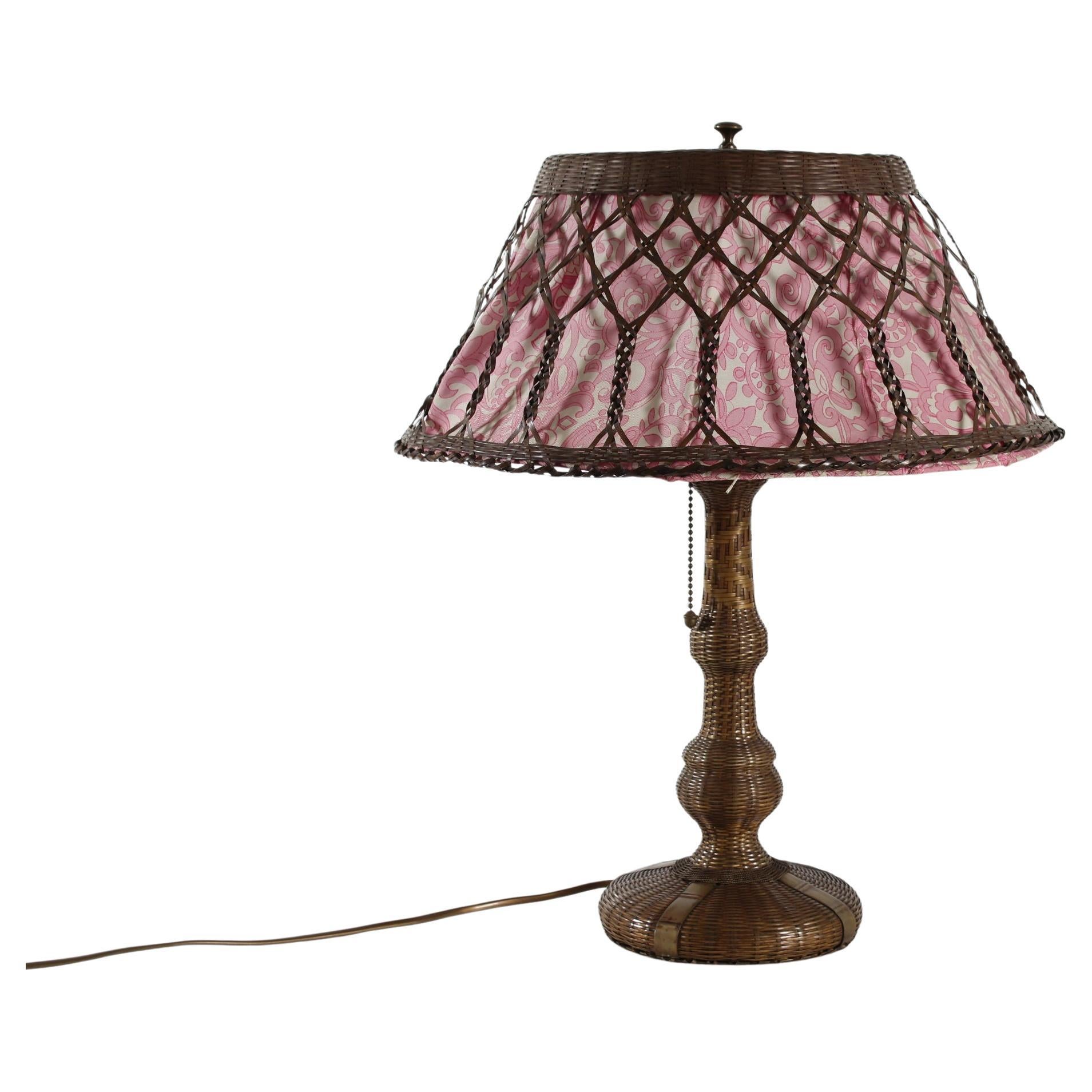 Arts and crafts pull chain table and desk lamp.
The base and frame of the shade are both made of brass with patina.
Plaited in a way that it looks like plaited cane/straw.
Inside of the shade frame is a lining of thin fabric with an floral