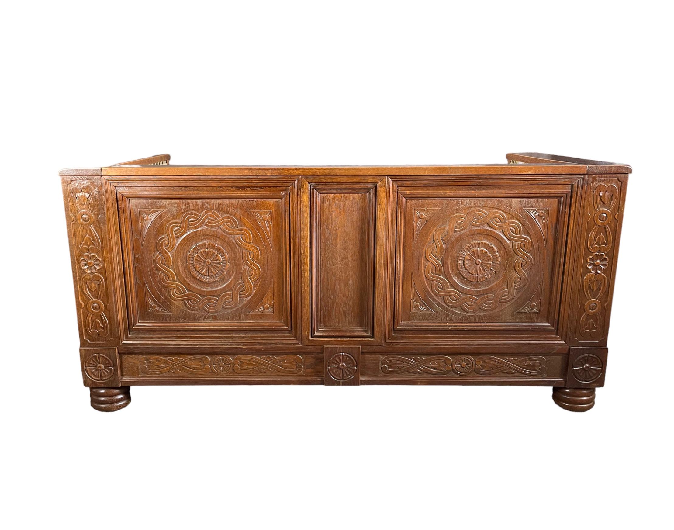 Arts & Crafts oak settle, with detailed carving to the front arms, the sides and back. The black wrought iron handles to each end, sturdy enough to lift this very heavy, solid piece. The spring base, still in excellent condition. 
A piece of