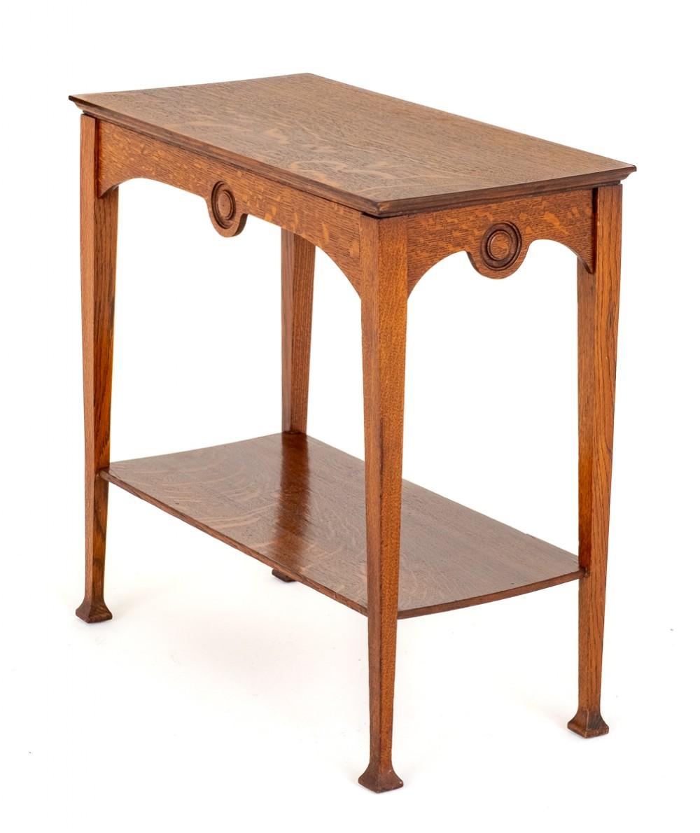 Arts and Crafts Oak Occasional Table.
Circa 1900
This Table is Raised Upon Tapered Legs With Typical Arts and Crafts Block Feet.The Table Has a Useful Undertray.
The Shaped Frieze Rails Featuring Turned Roundels.
The Oak Top Having Figures Rays