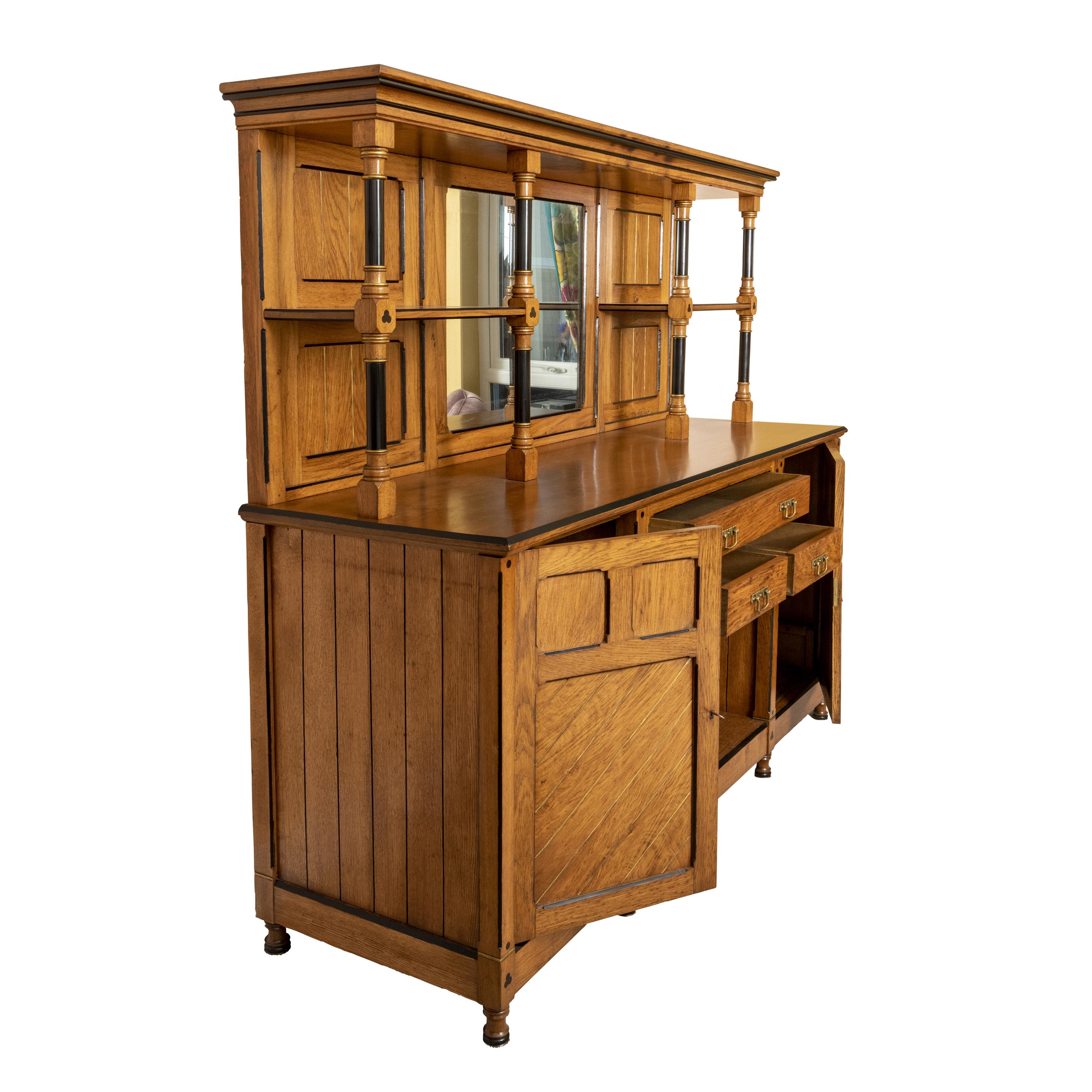 Arts and Crafts aesthetic Sideboard possibly by Charles Bevan.
Oak, walnut, ebony, satinwood.
Shaped apron back above a frieze with three drawers.
The base with 2 cupboard, the doors with recessed shaped walnut panels carved and embossed with
