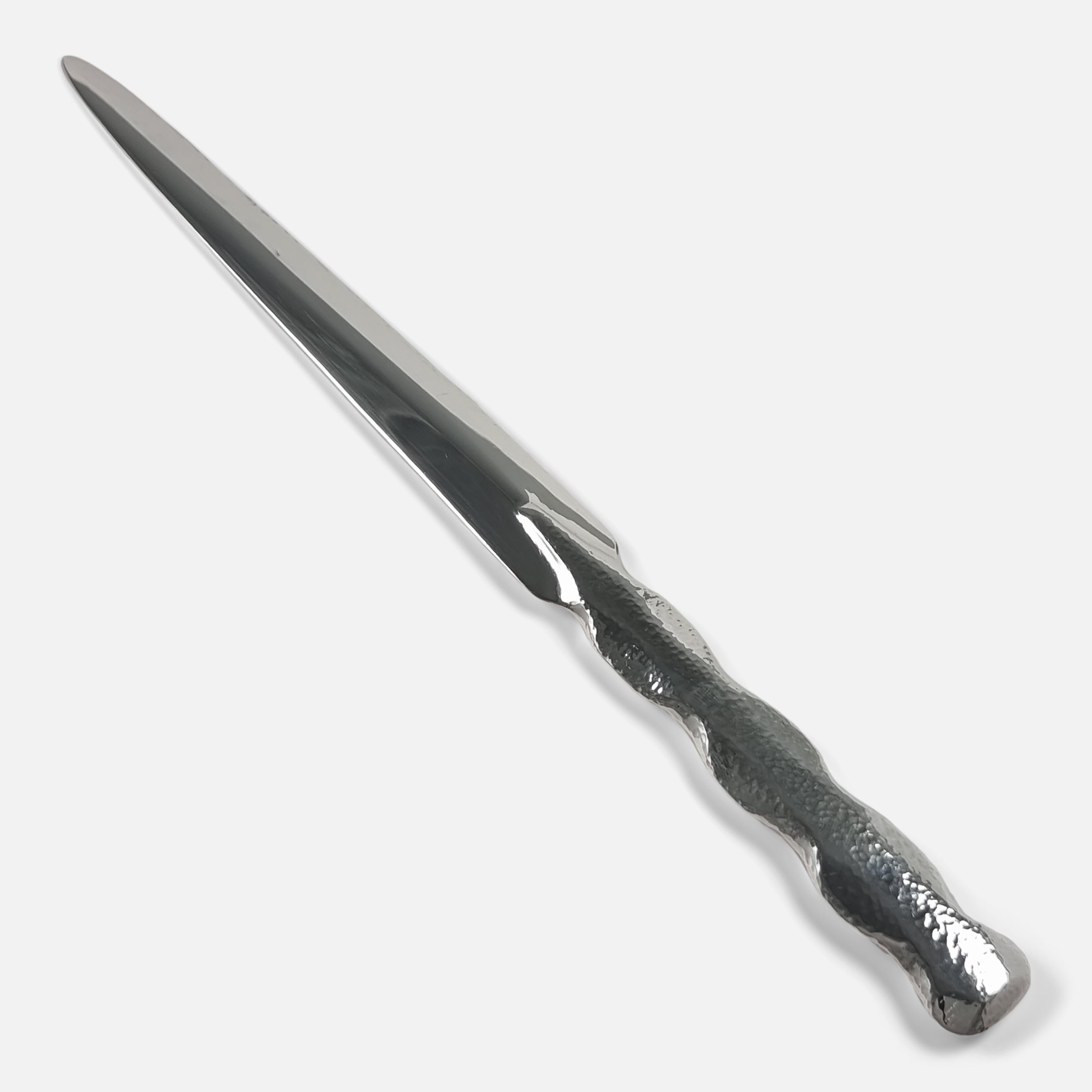 An Arts & Crafts sterling silver paper knife (or letter opener) by Omar Ramsden. The paper knife is crafted with a tapering blade, wavy-edge handle, and spot-hammered decoration.

It is hallmarked with London marks, 1938.

Assay: - .925 Sterling