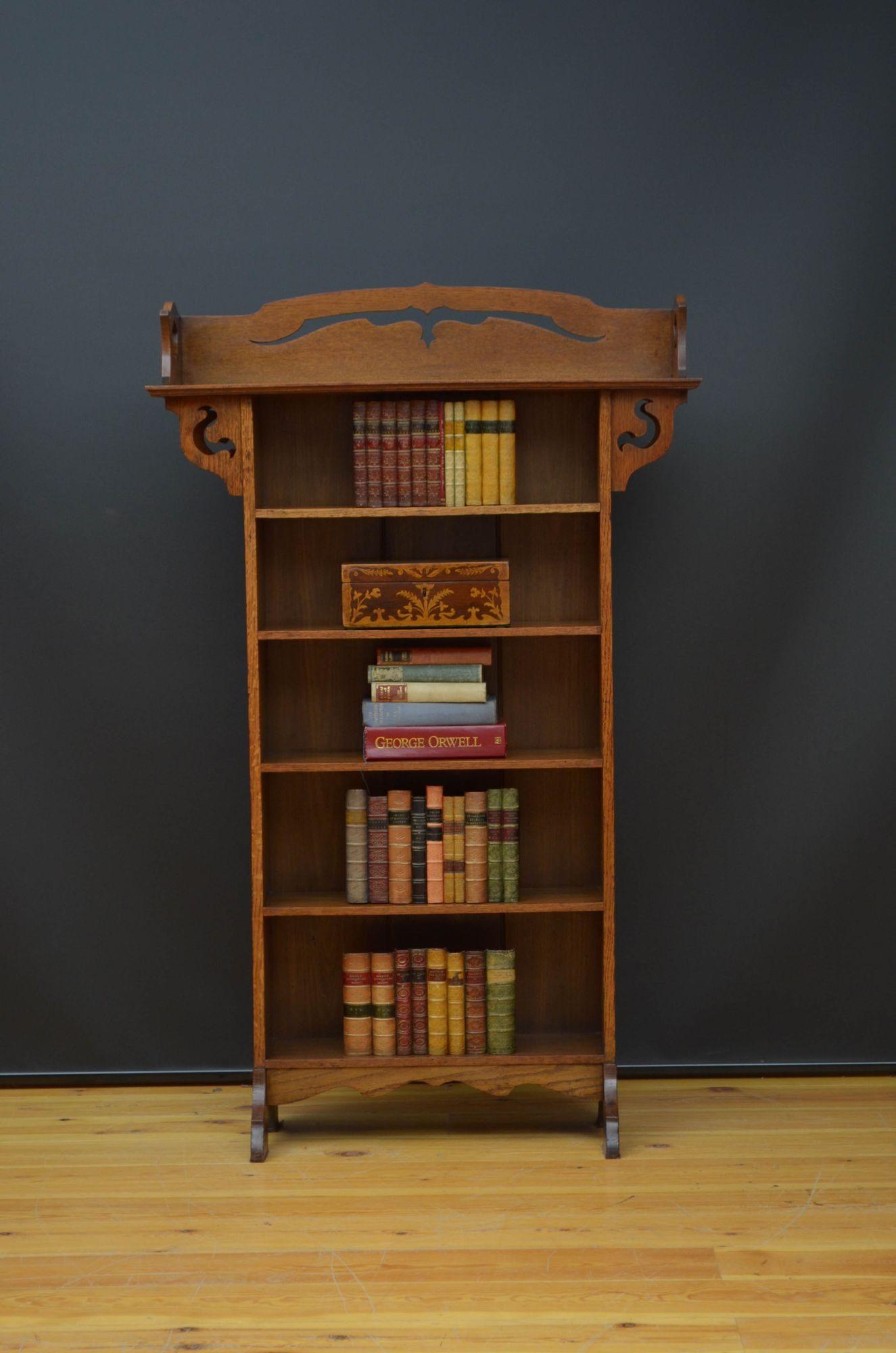 Sn5457 Stylish Arts and Crafts open bookcase in solid oak, having shaped upstand to the top above four decorative carved brackets and five shelves, standing on shaped legs united by serpentine apron. This antique bookcase retains its original