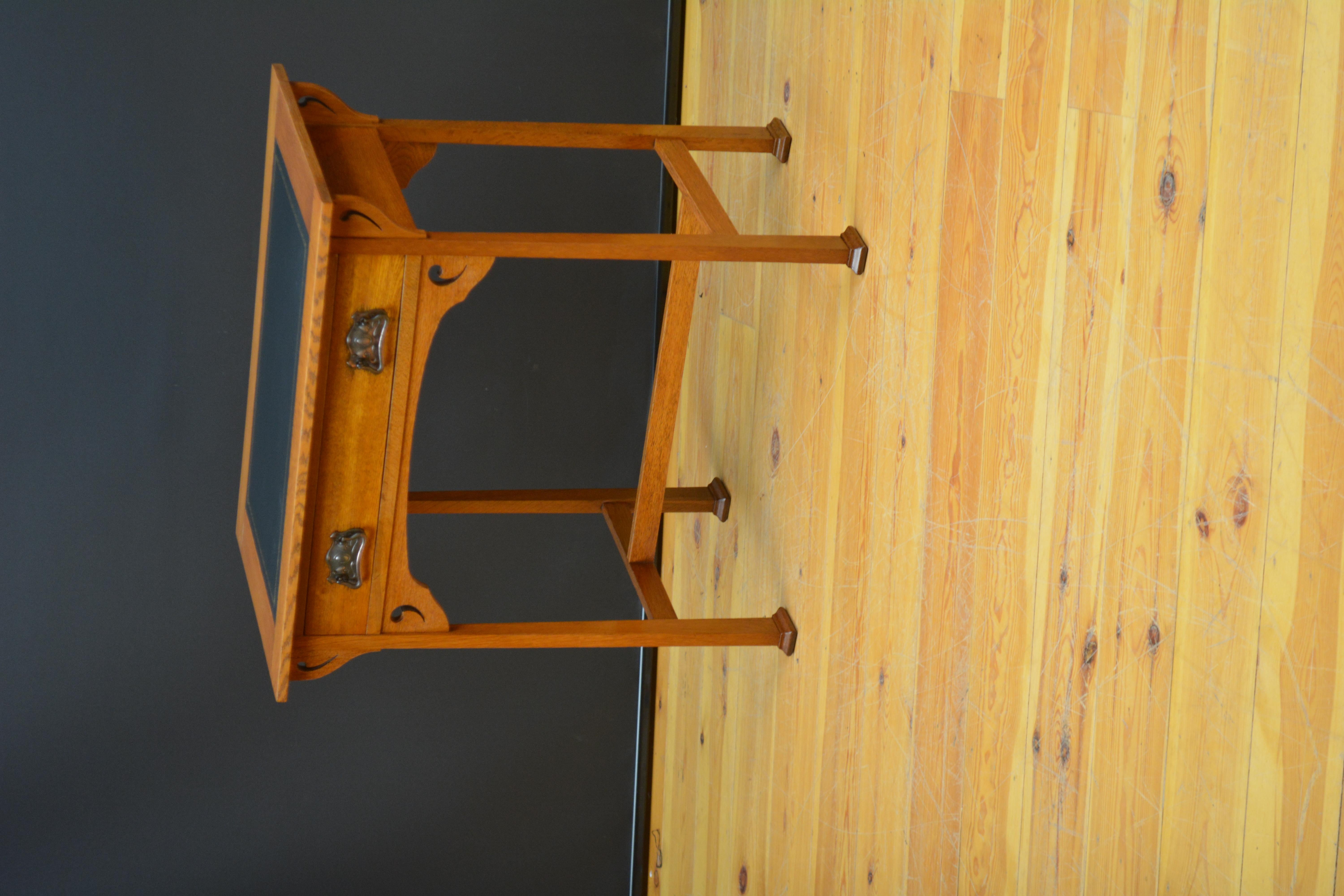 Sn5657 Stylish Arts and Crafts solid oak table, having new black tooled leather writing surface above oak lined drawer fitted with excellent original handles flanked by shaped carving, standing on square legs terminating in pad feet, polished to