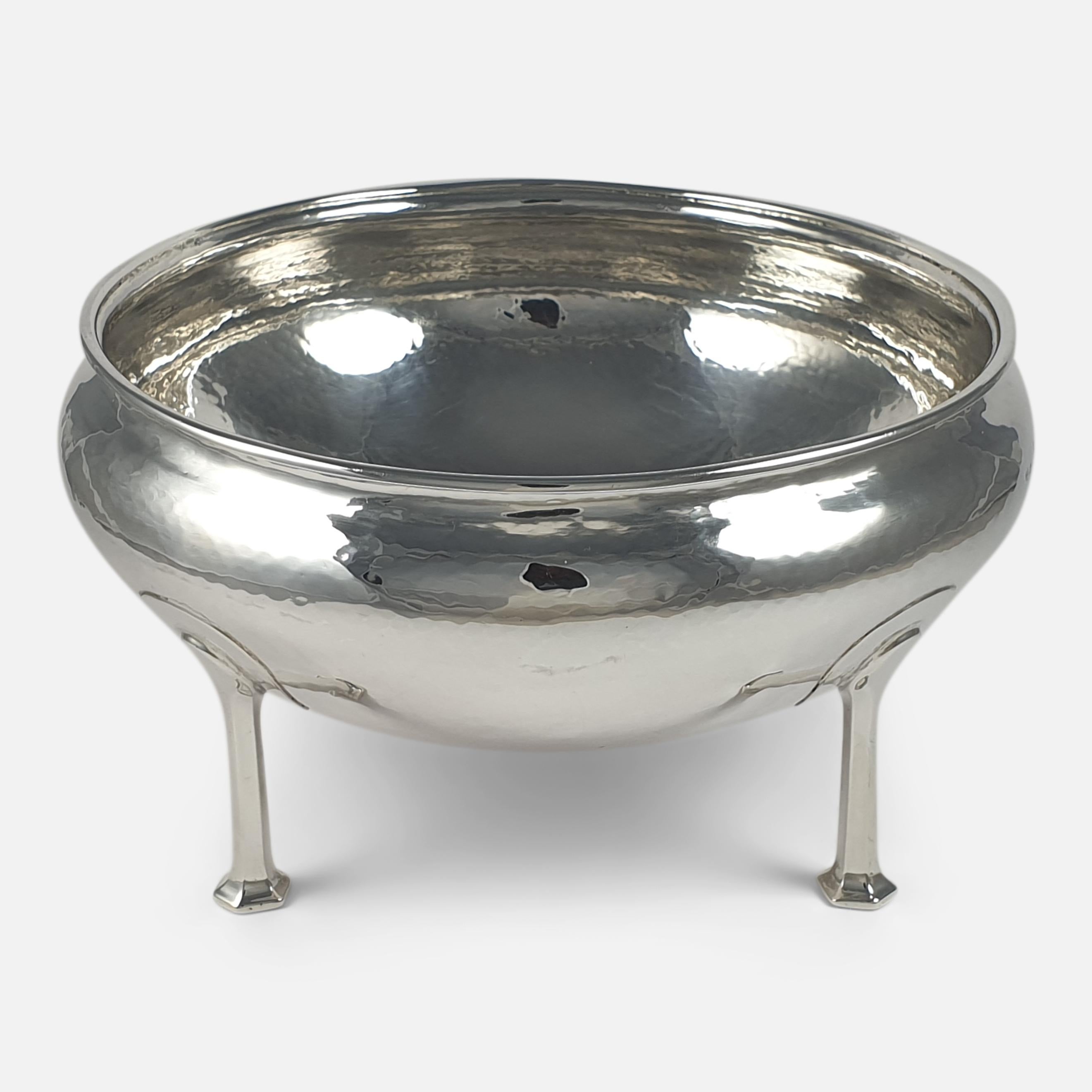 A George V sterling silver Arts & Crafts bowl by A. E. Jones, Birmingham, 1912. The bowl is of circular form, with spot-hammered decoration, applied moulded border to the rim of the body, and sitting on four long hexagonal bracket feet.

Assay: