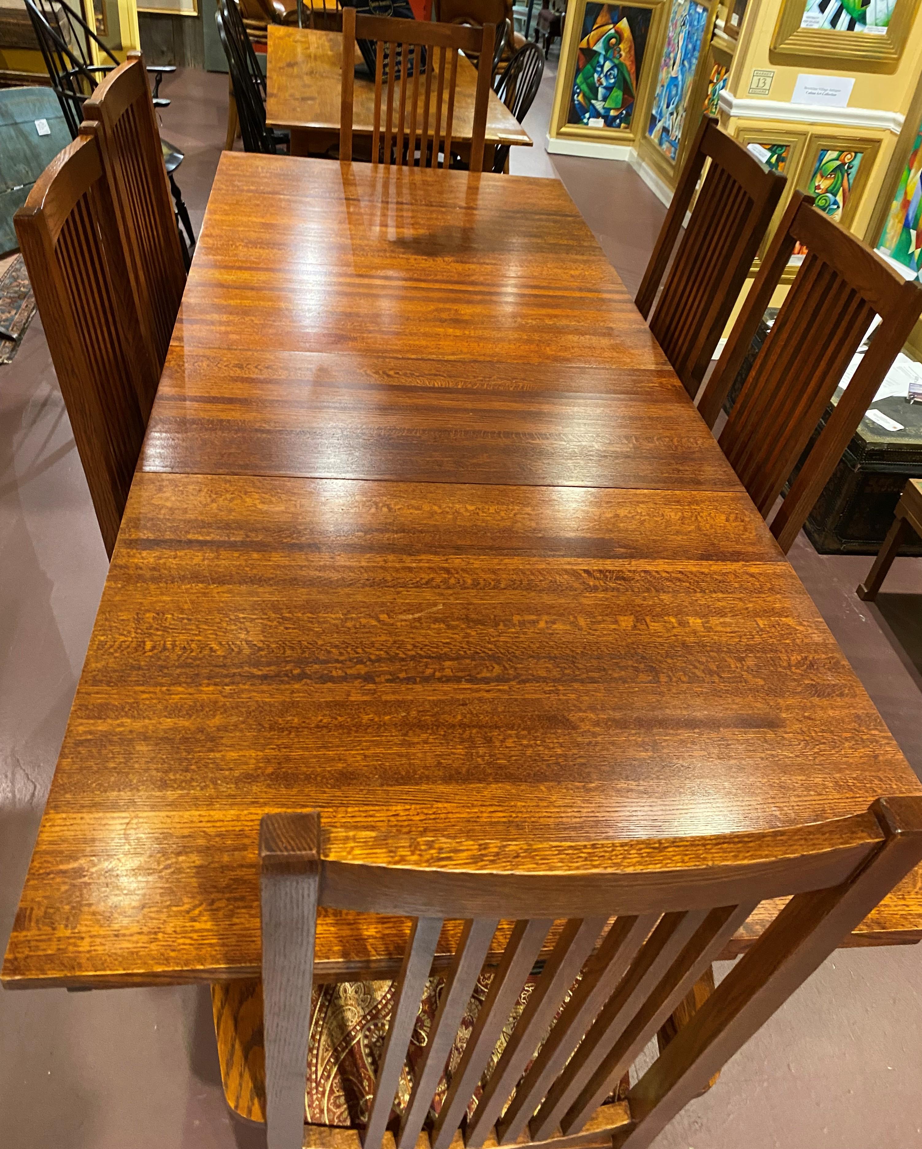 A fine mission arts and crafts style dining room set by Michaels Company of Sacramento, CA including a rectangular oak dining table with two 18 inch finished leaves with aprons and six matching tall back dining chairs (two arm chairs and six side