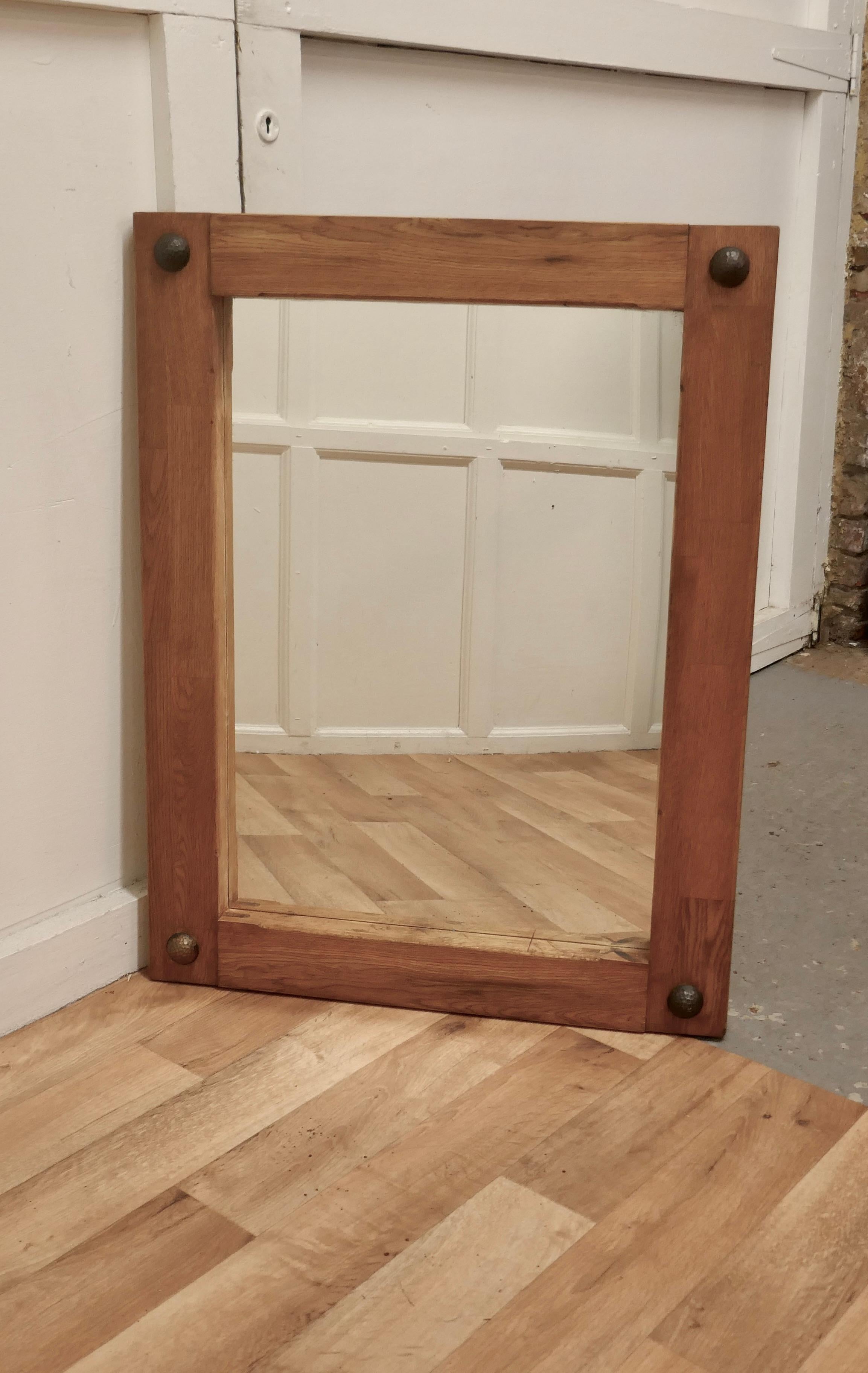 Arts & Crafts style golden oak wall mirror 

This is an unusual piece, the mirror is made in Golden oak, the frame is 3.5” wide with beaten iron roundels in each corner
The mirror and frame are both in good condition
The mirror is 34” high, 26”