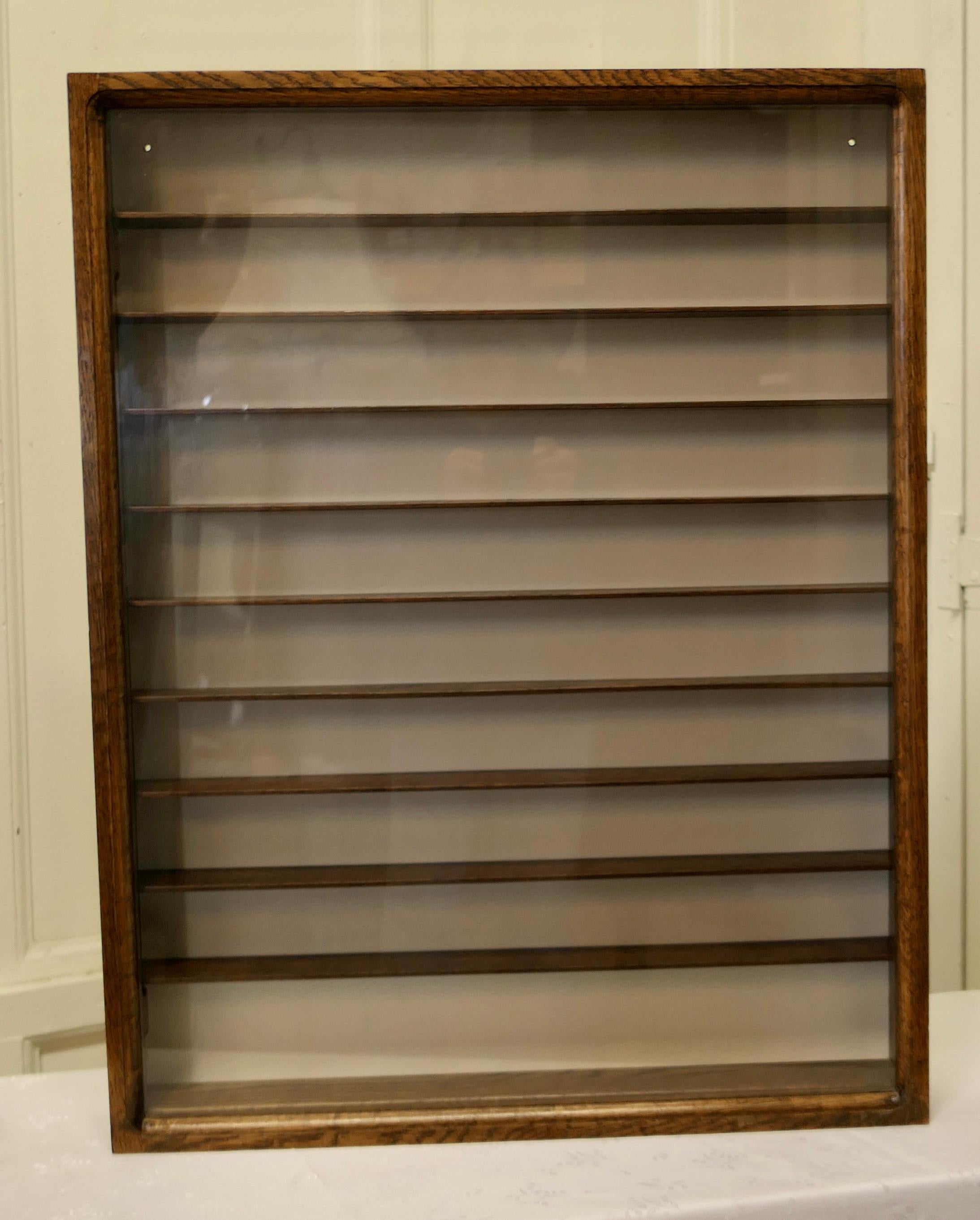 Arts & Crafts/ table top wall hanging collectors display cabinet.

This is quite a shallow wall hanging cupboard, the inside is 2.5” deep with shelves that are between 2.5” and 3.5” apart and it has a fully glazed door. 
The cabinet has an Oak