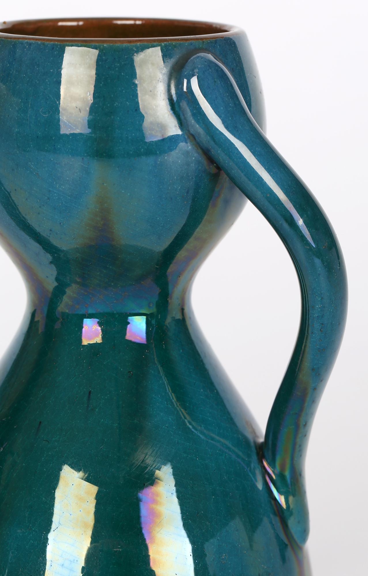 Un superbe vase en forme de sablier à trois anses, de style Arts & Crafts, attribué à Linthorpe et à la manière de Christopher Dresser (britannique, 1834 - 1904), datant d'environ 1880. Le vase repose sur une base plate émaillée et se compose de