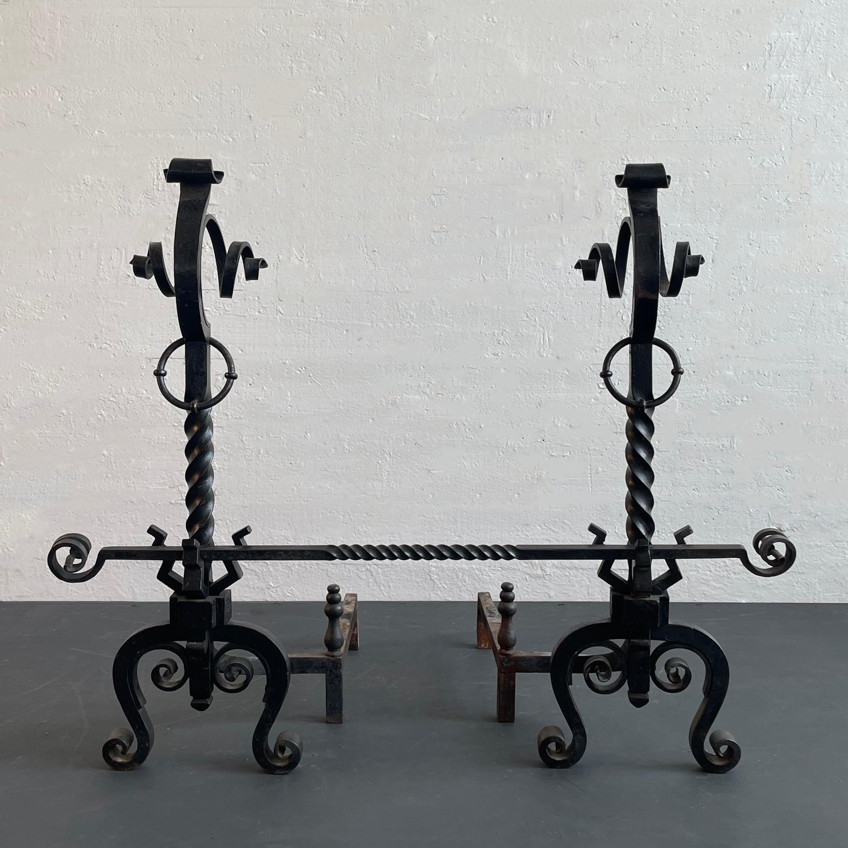 Impressive, early 20th century, Arts And Crafts, hand-wrought iron, andiron set is comprised of two andirons and a crossbar at 38 inches wide. The set features twisted stems with scrolled flourishes and ring loops. This three piece set is a