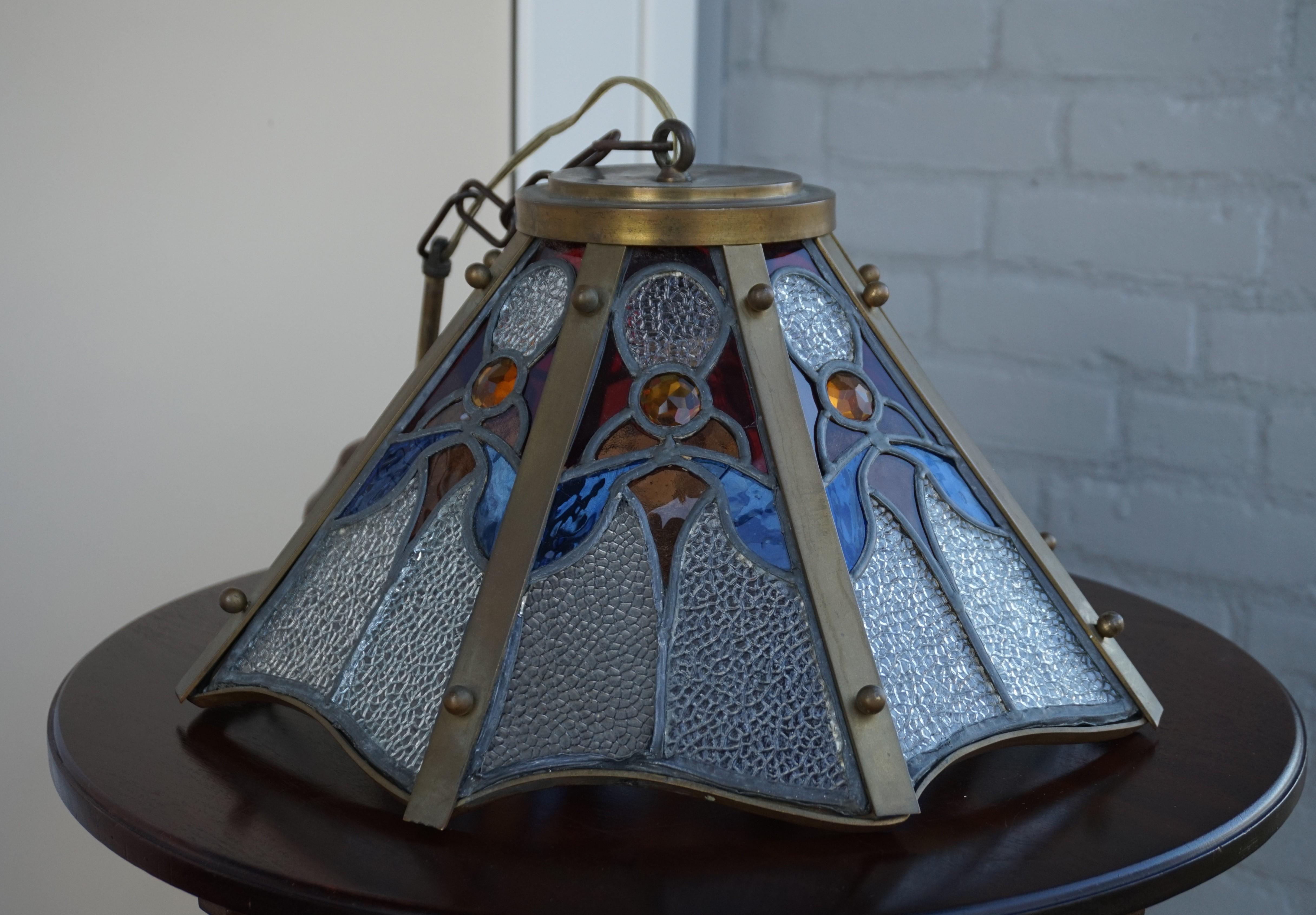 One of a kind and all-handcrafted antique pendant.

This antique light fixture comes with a beautiful Arts & Crafts motif in each of its eight stained glass panels. Both in terms of colors and shape, the stylized flower motif really is a joy to