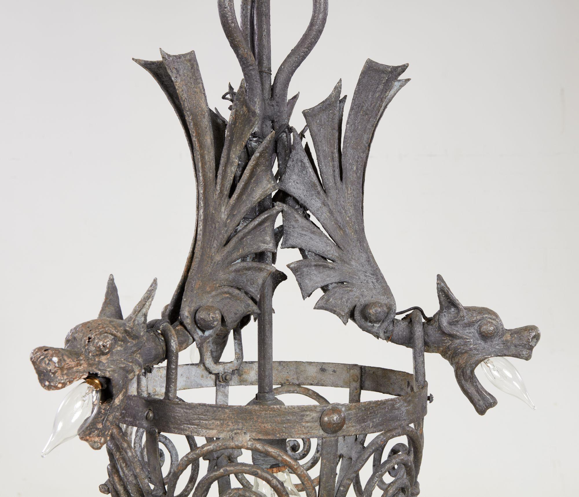 Fantastic early 20th century wrought iron chandelier in the manner of Samuel Yellin, having three dragon gargoyles over scrolled iron basket, each dragon with single chandelier bulb and the center with full size light bulb socket.
Samuel Yellin, a