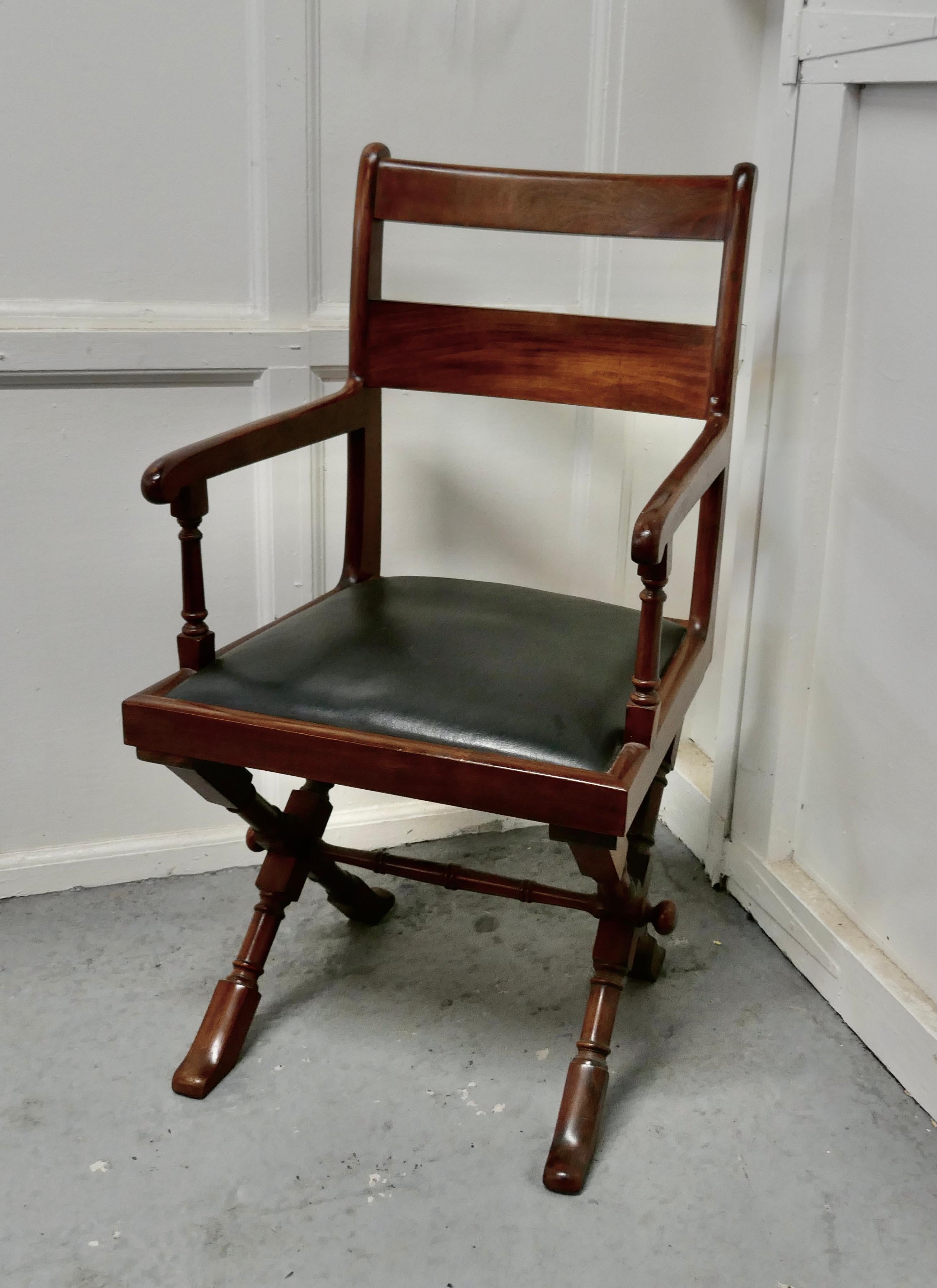 Arts & Crafts X-frame mahogany desk chair.

The chair is set on X-framed Legs, a very strong design, it has elegant arm rests and double bar rack rest 
This roomy and stylish chair has black leather upholstery all of which is in good condition