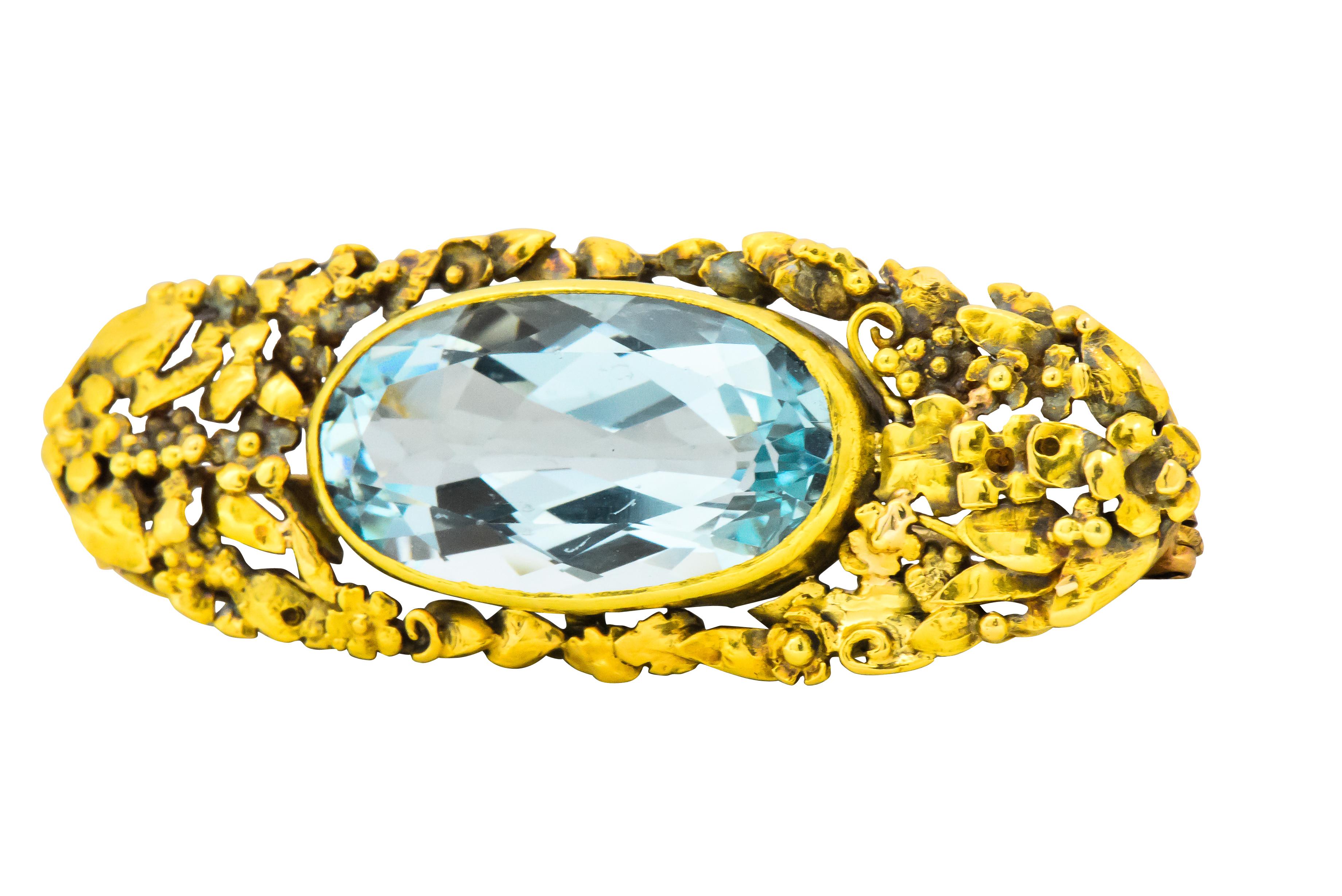 Centering an oval aquamarine weighing approximately 12.55 carats, very very slightly greenish blue 

Bezel set east to west

Highly detailed openwork foliate motif setting with leaves, flowers, and grapes

Tested as 14 karat gold

Circa