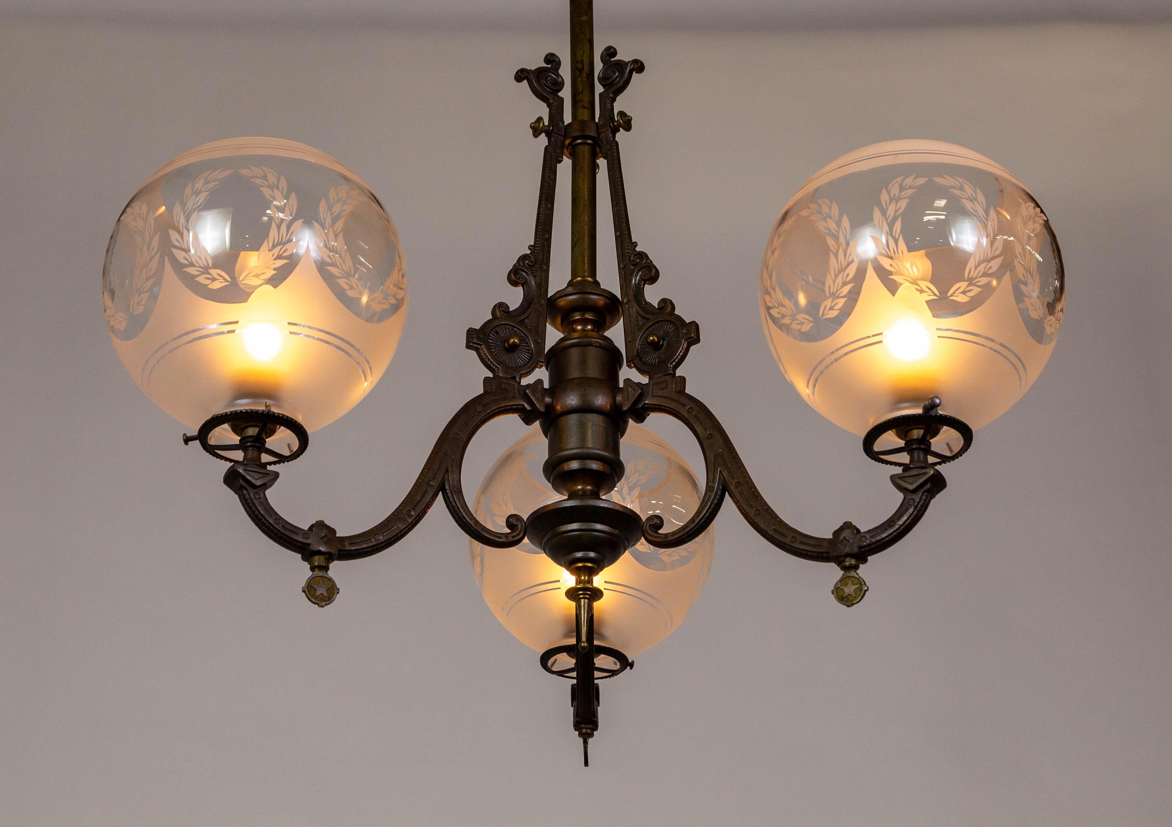 A finely cast, iron and brass Arts & Crafts chandelier with refined, geometric details and Eastlake styling.  This late 19th-century chandelier was formerly gas-lit and has been newly rewired.  The structure has a rich, dark patina and holds three