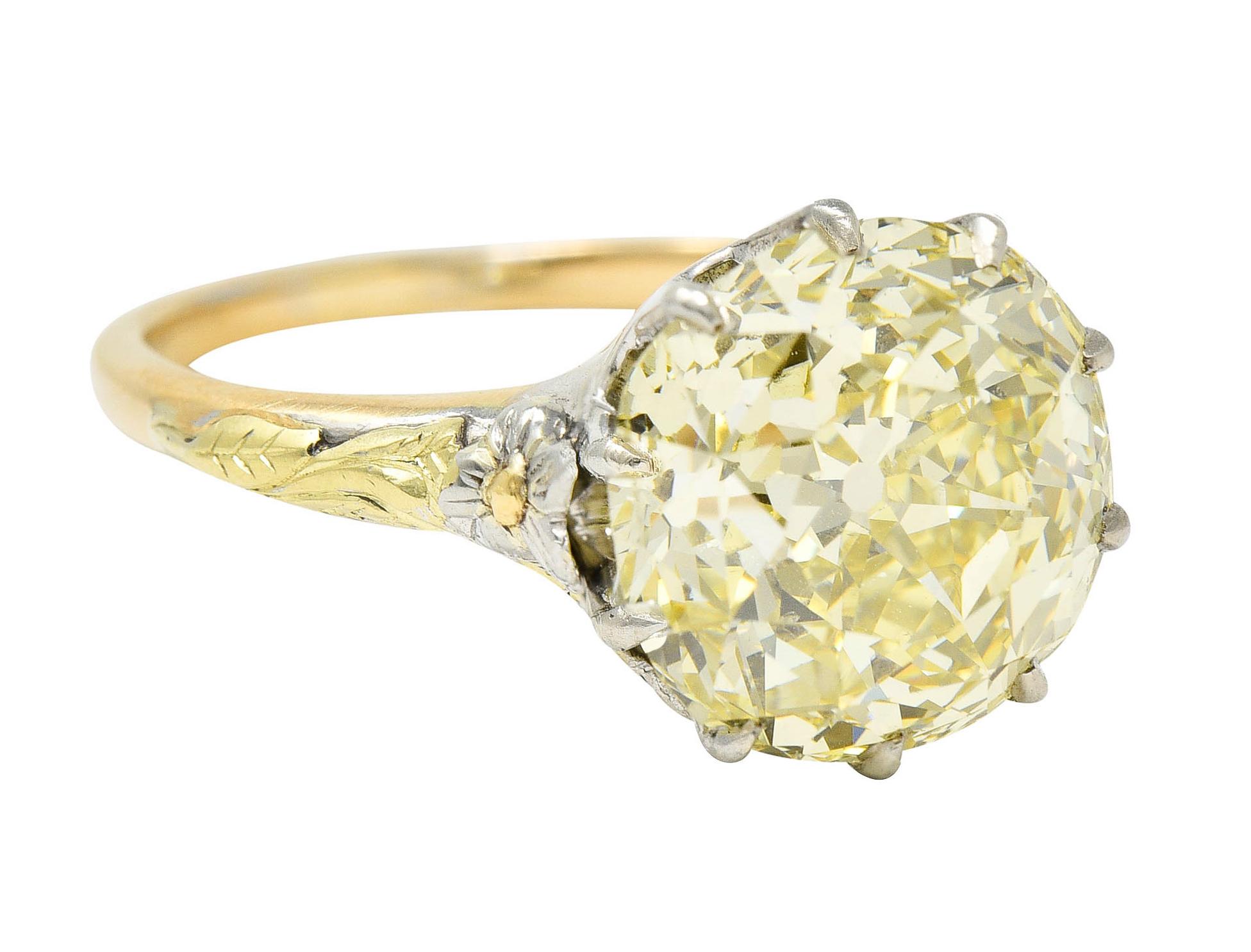 Centering a cushion modified brilliant cut diamond weighing 7.12 carats

Natural fancy yellow in color with SI2 clarity

Talon set in a white gold head and flanked by highly rendered tri-colored gold florals

Completed by a yellow gold