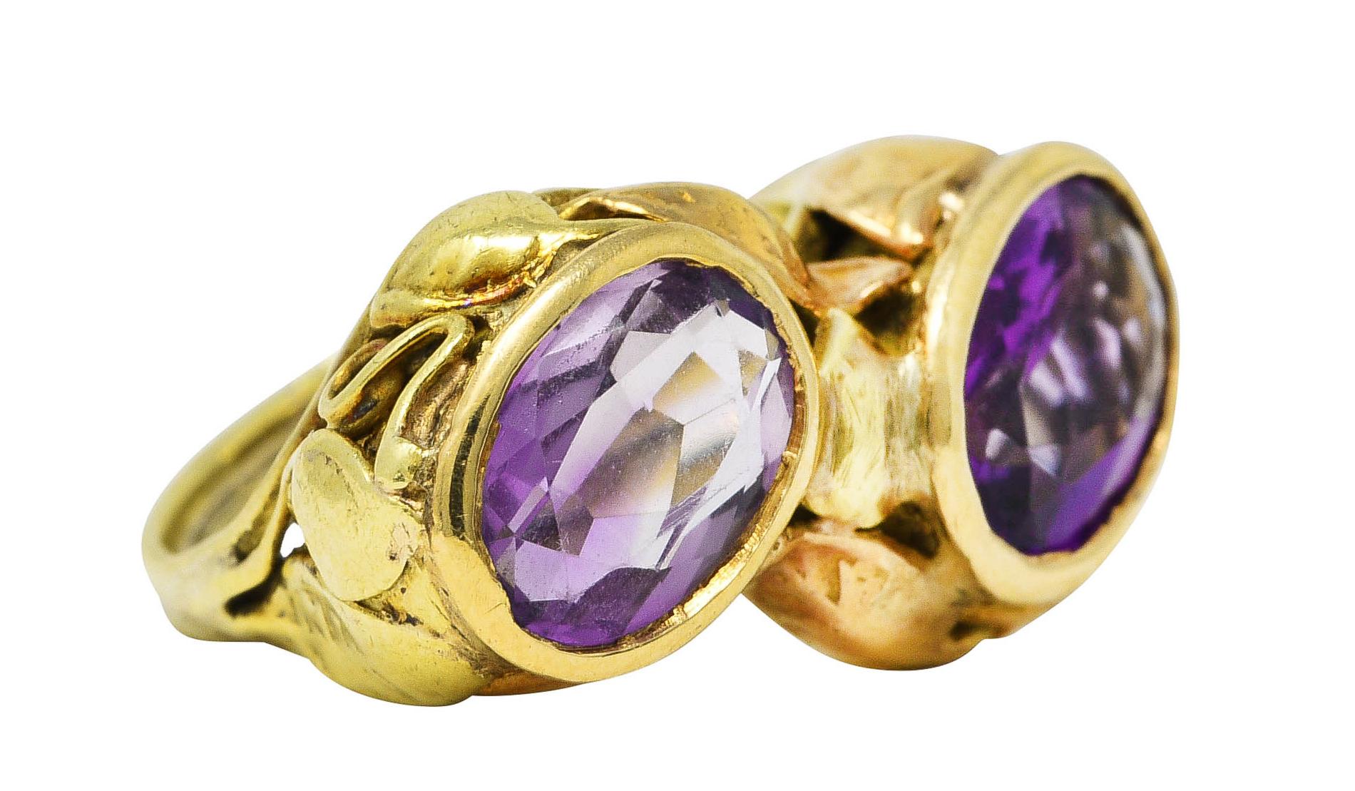 Ring features two bezel set oval cut amethysts measuring 6.4 x 9.0 mm and 6.6 x 9.2 mm. Transparent purple - one with light saturation and one with medium saturation. With highly rendered yellow and rose gold foliate surround. Tested as 14 karat