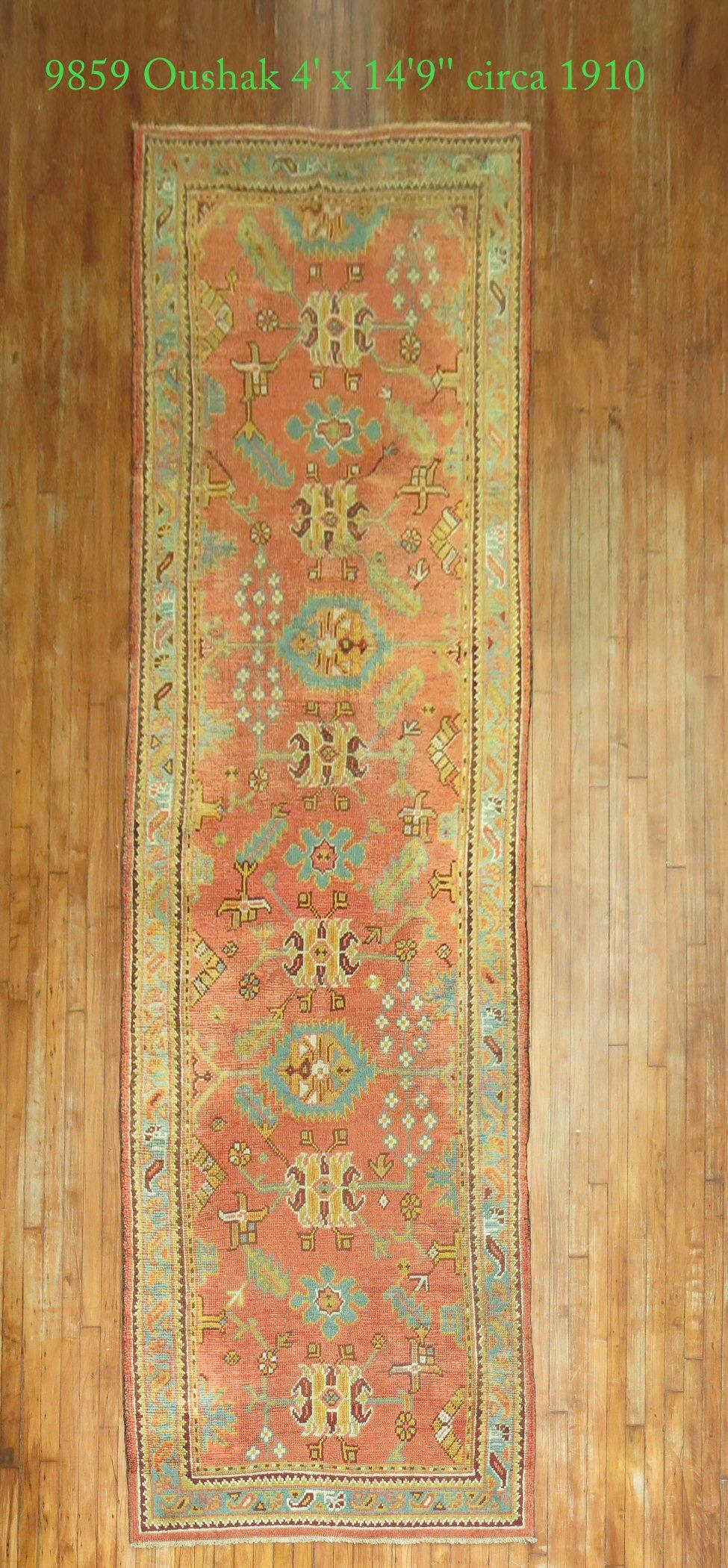 An early 20th-century antique Oushak runner featuring a pumpkin orange field, the green border with an all-over design attributed to the Arts & Crafts movement.

Measures: 4'”x 14'9”.