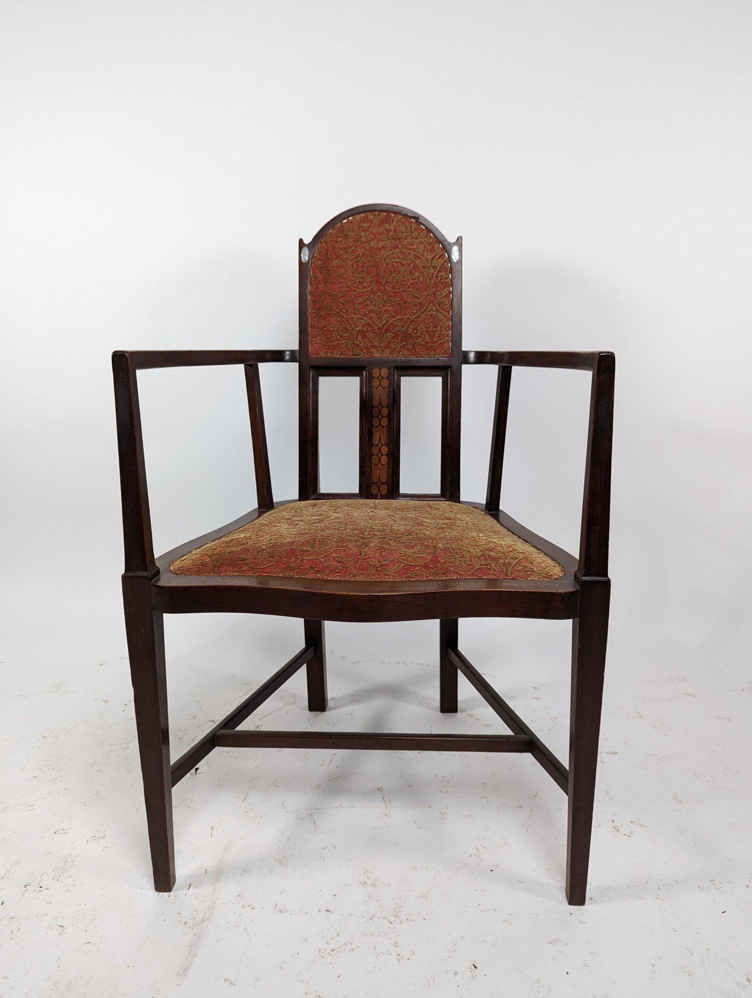 An armchair designed by George Montague Ellwood and made by J S Henry, with arched top and oval mother-of-pearl inlays just below the ears and sinuous arms with conforming seat details to the side and subtle curve to the front and extra